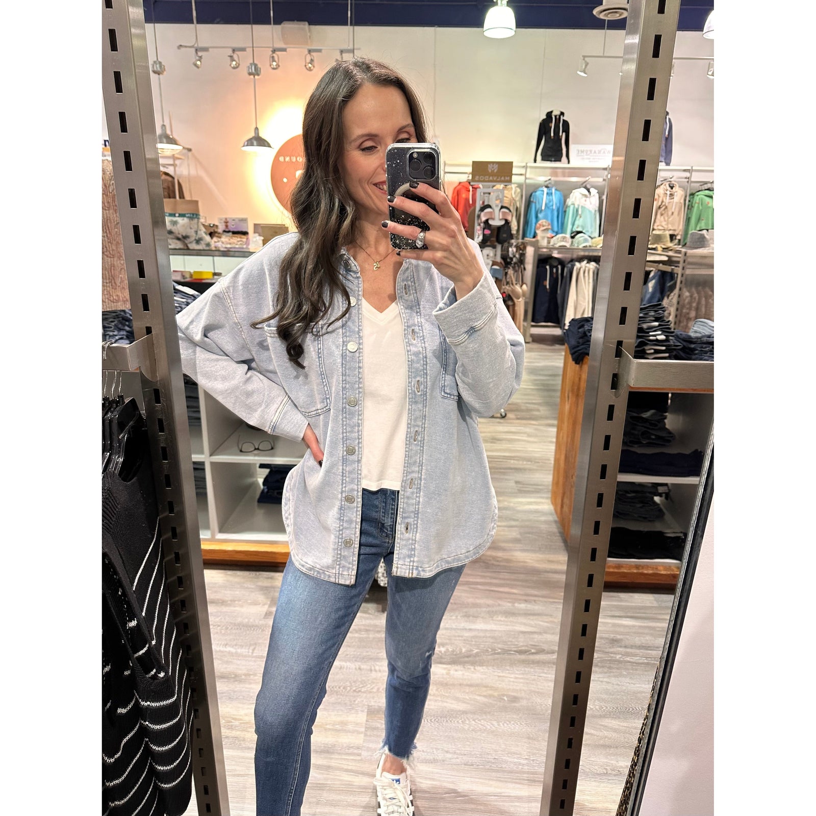 Woman wearing Z Supply All Day Knit Denim Jacket in light wash over white tee in a clothing store.