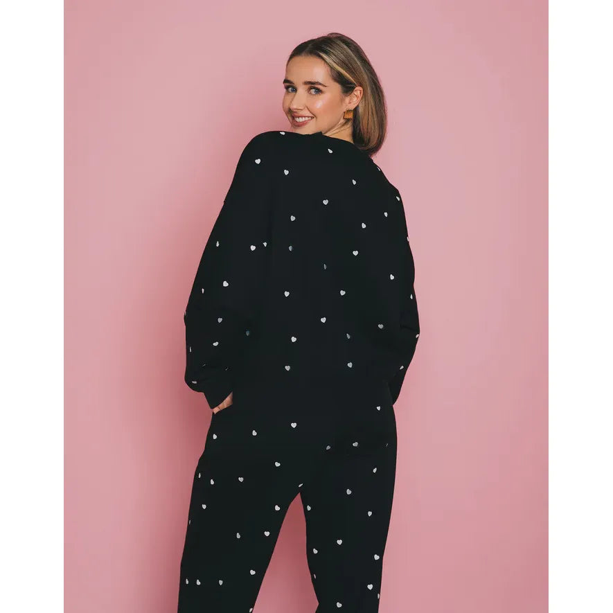 Brunette the Label All Over Tiny Heart Crew black loungewear with white tiny hearts, model posing against pink backdrop