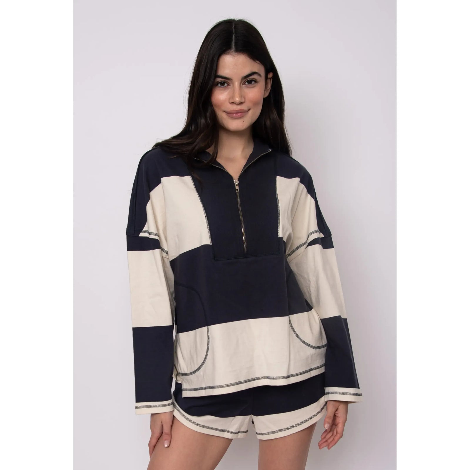 Model wearing Camille Striped 1/2 Zip Rugby Shirt in navy and cream color-block stripes.