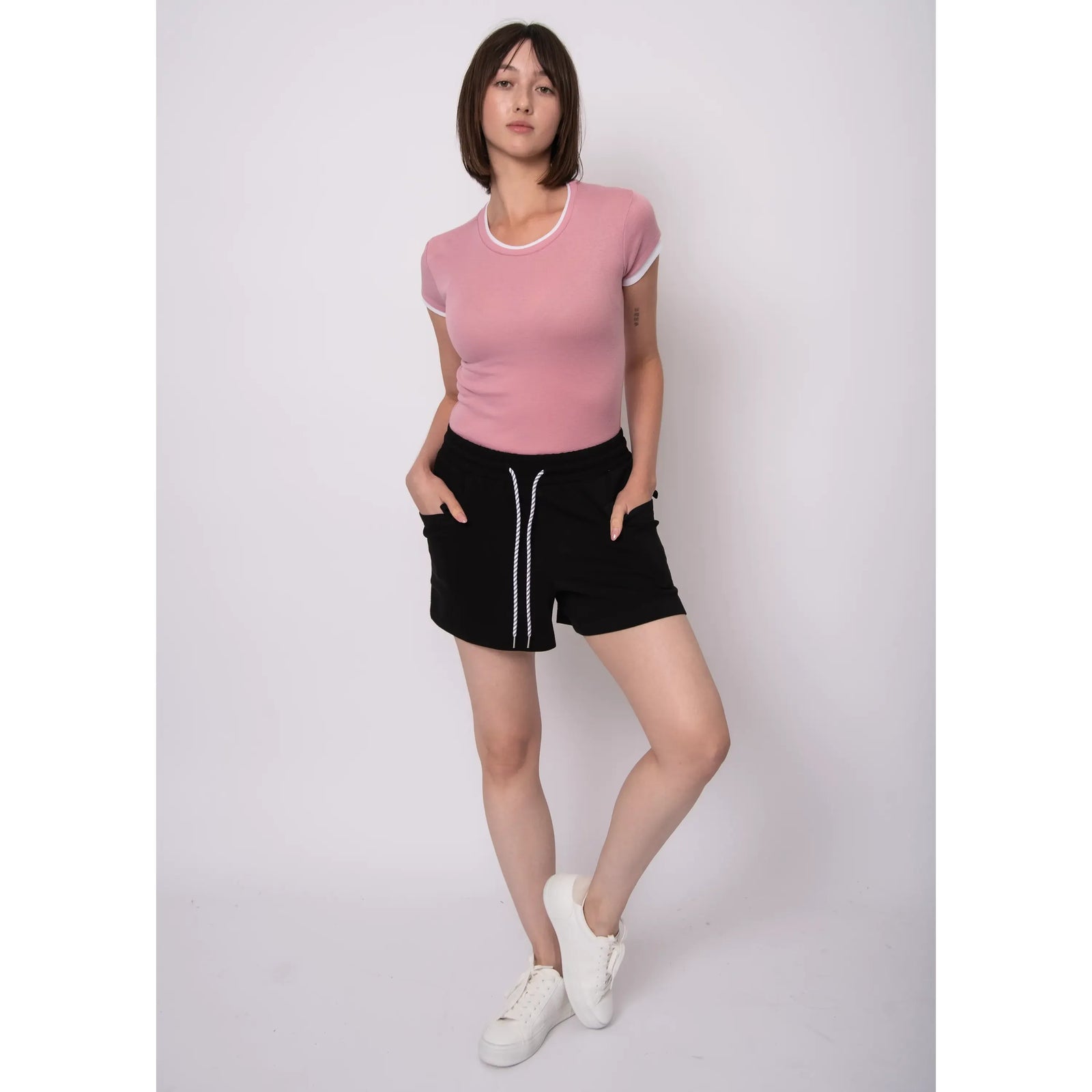 Model wearing Darcia Soft Knit Drawstring Shorts in black with white drawstring, pink top, white sneakers.