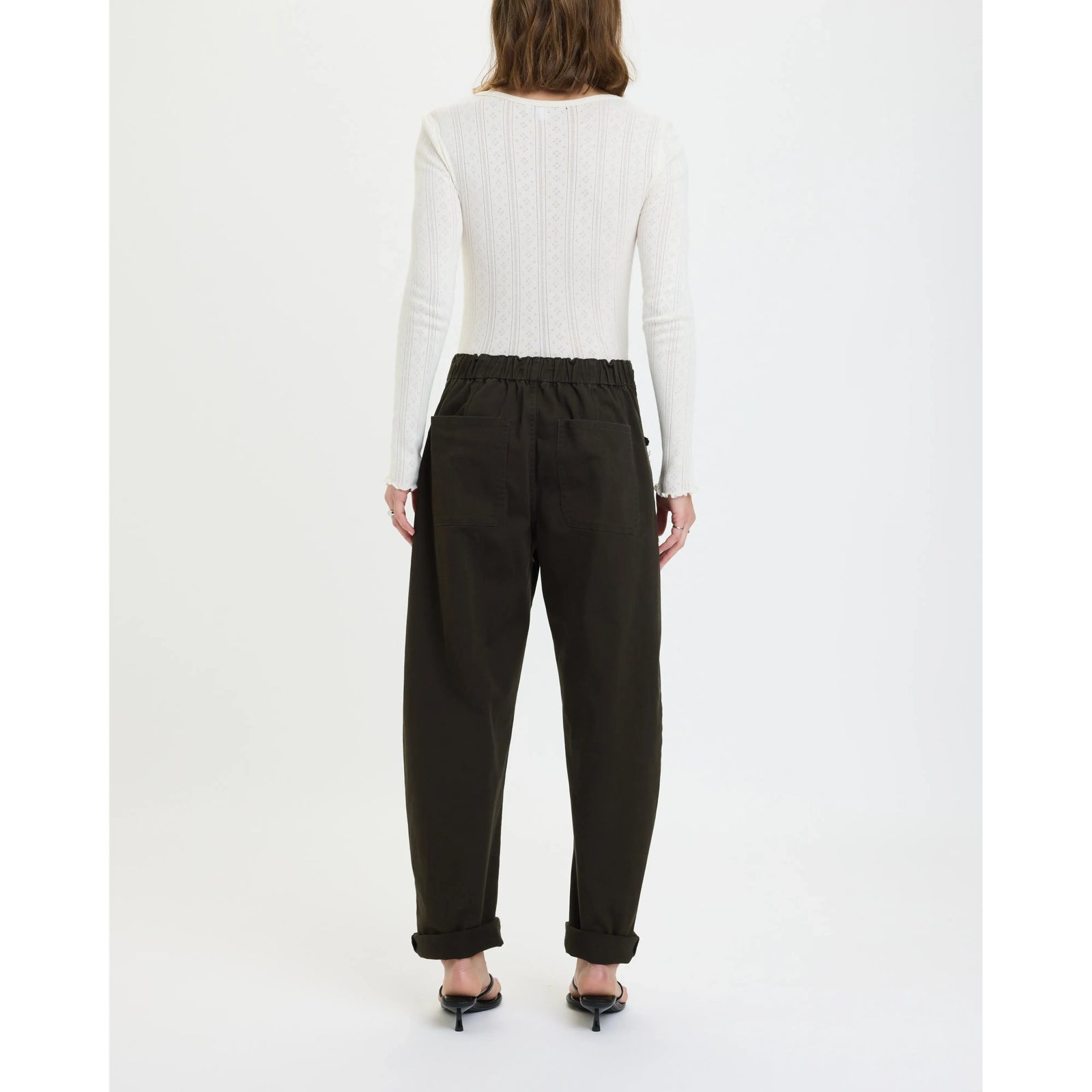 Back view: Daze Villa Drawstring Barrel Pant in Fern with elastic waist and tapered legs, worn with a white knit top.