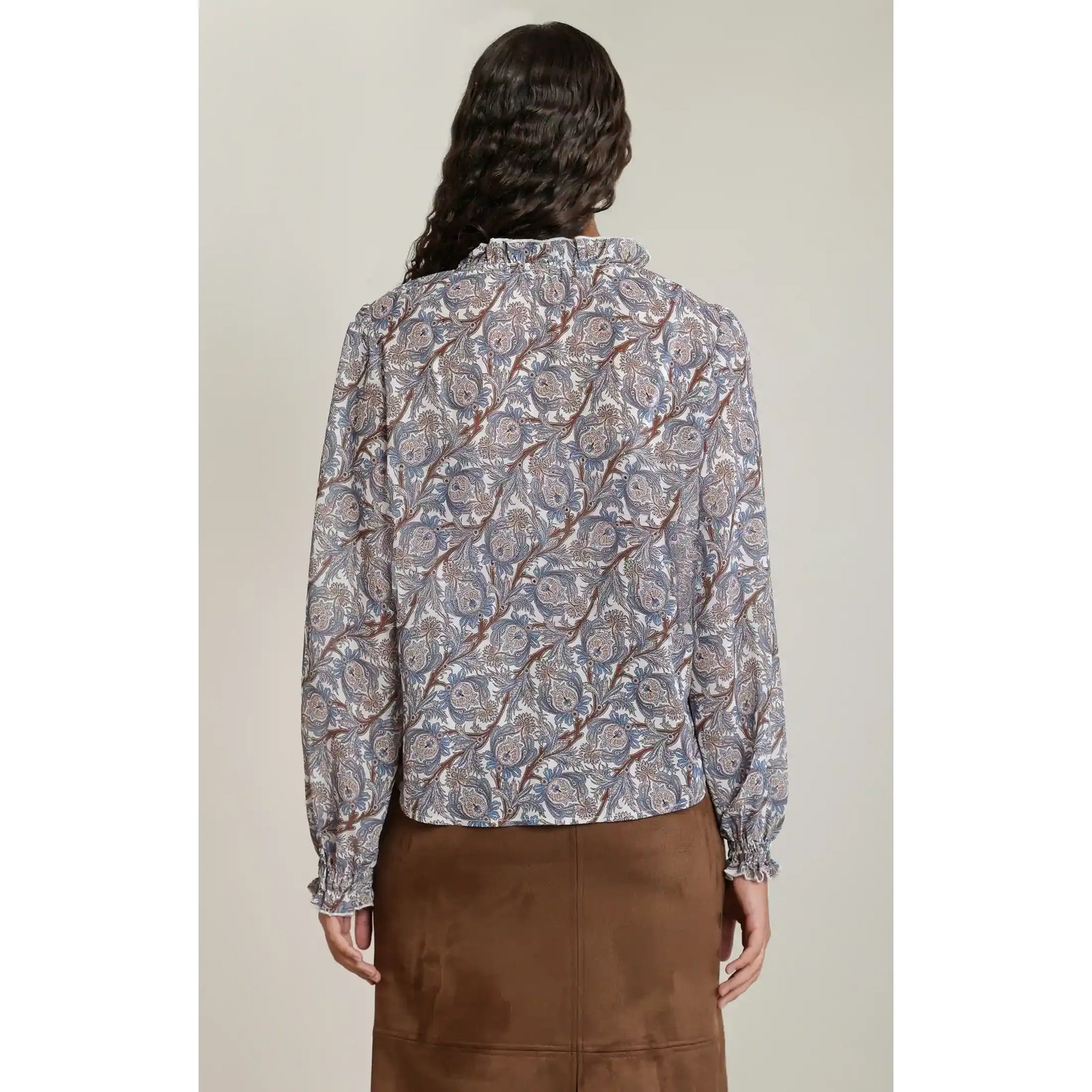 Back view of a blue and brown floral print balloon sleeve blouse with elasticized cuffs and a ruched neckline.