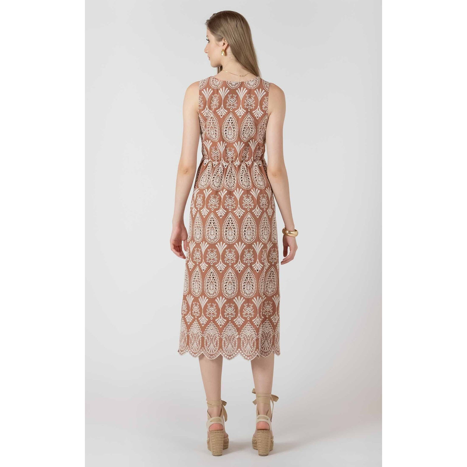 Dex Black Tape V Neck Eyelet Dress on model, back view in brown fabric with white eyelet pattern and scalloped hem.