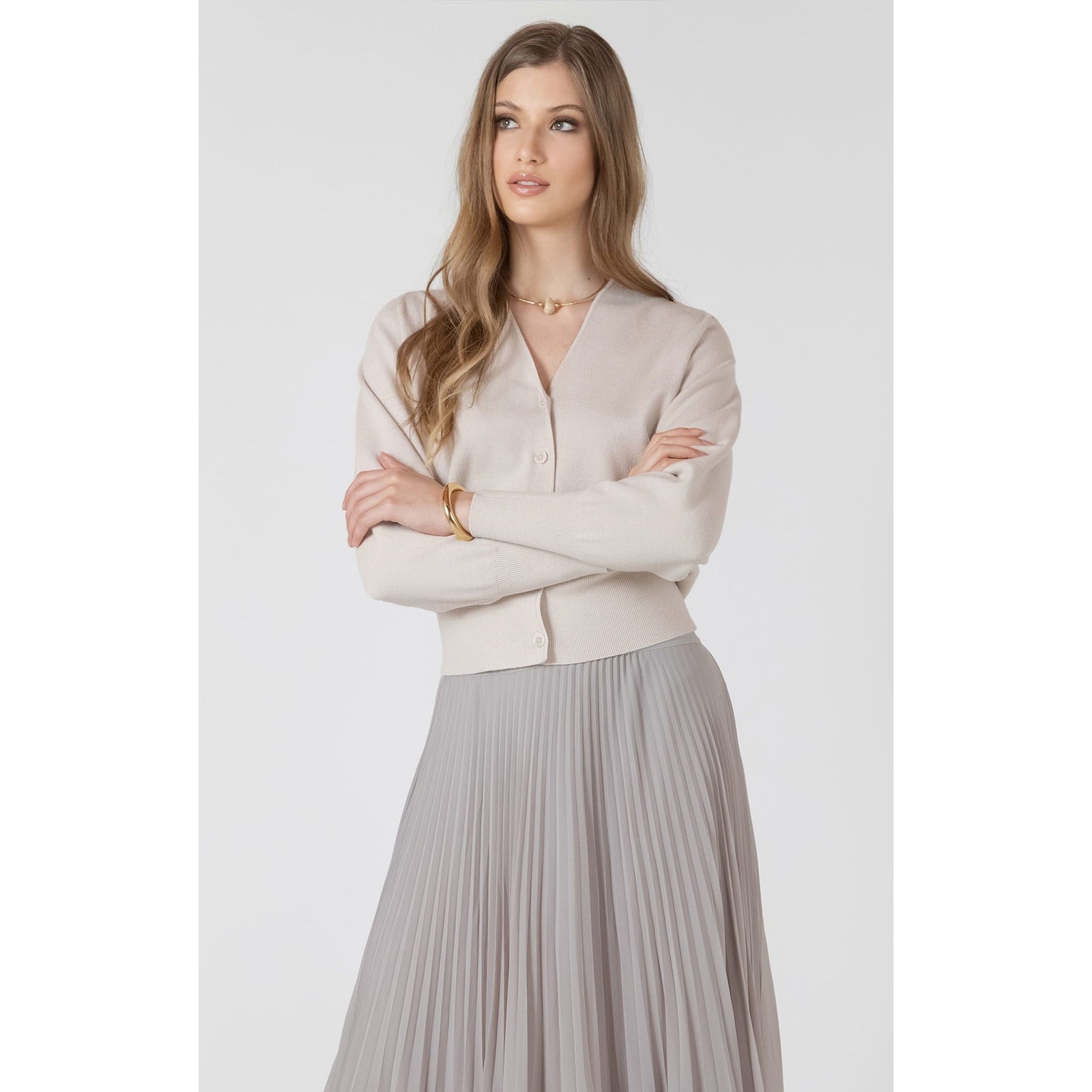 Dex Button Front Cardigan in soft beige with clean lines and button front, paired with a light gray pleated skirt.