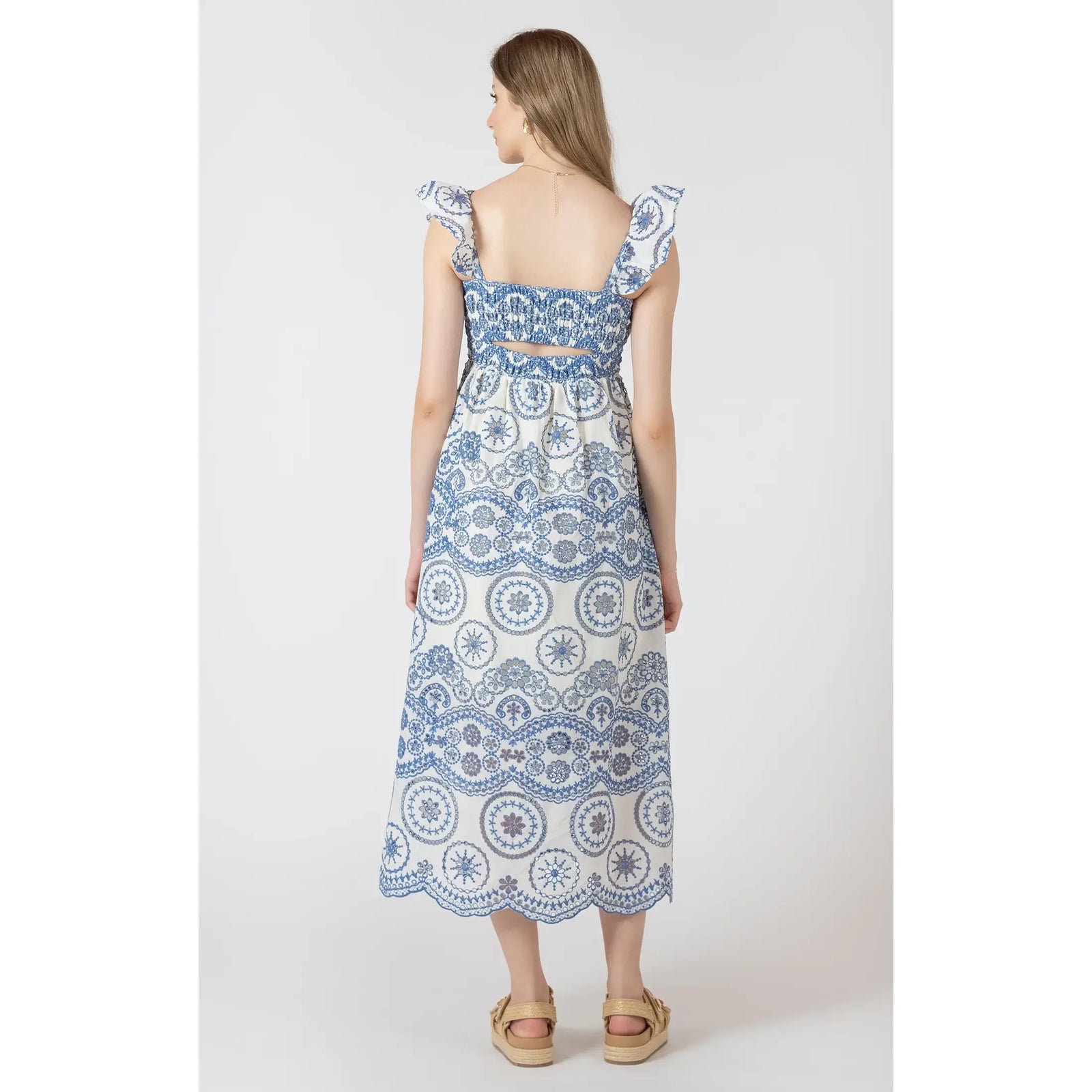 Model wearing Dex V Cutout Embroidered Dress; blue-and-white printed maxi with V-waist and flutter sleeves.