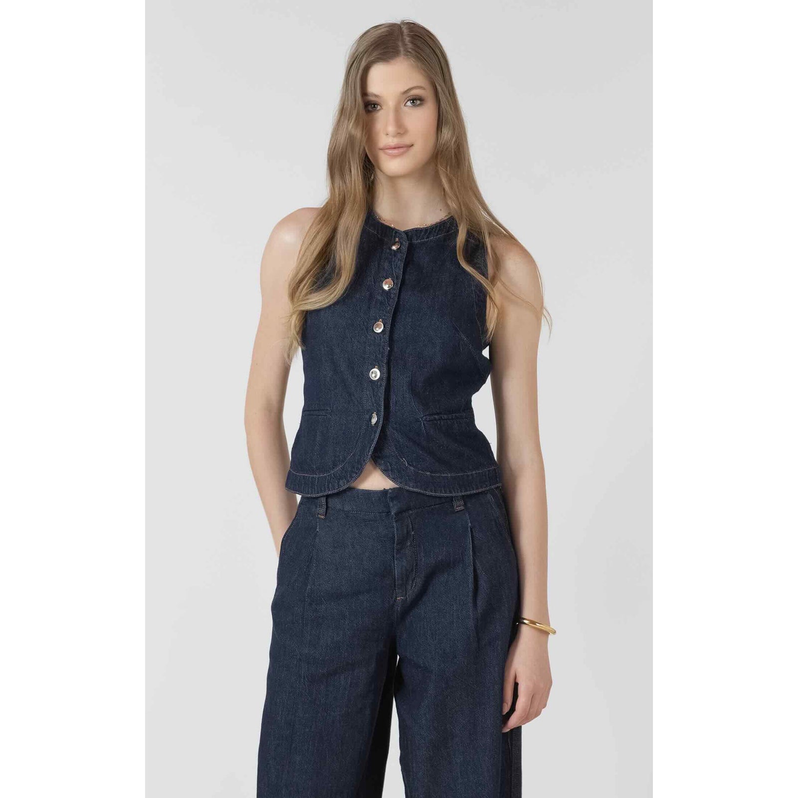 Dex Black Tape Denim Vest on a model, dark indigo sleeveless button-up denim top with curved hem.