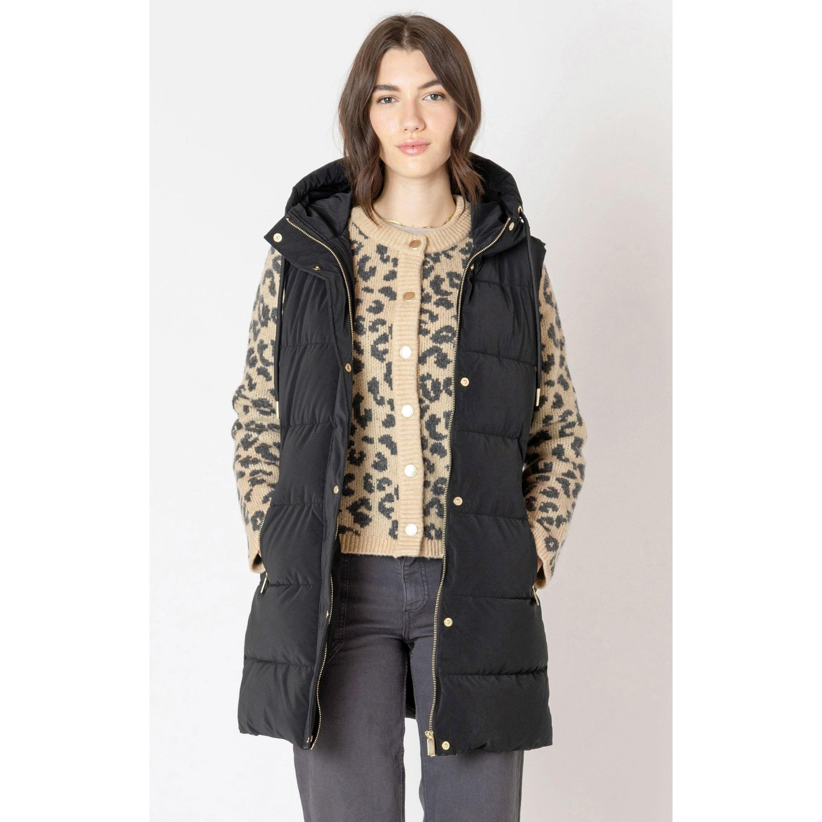 Dex Hooded Puffer Vest on model, black quilted hooded vest layered over a leopard cardigan.