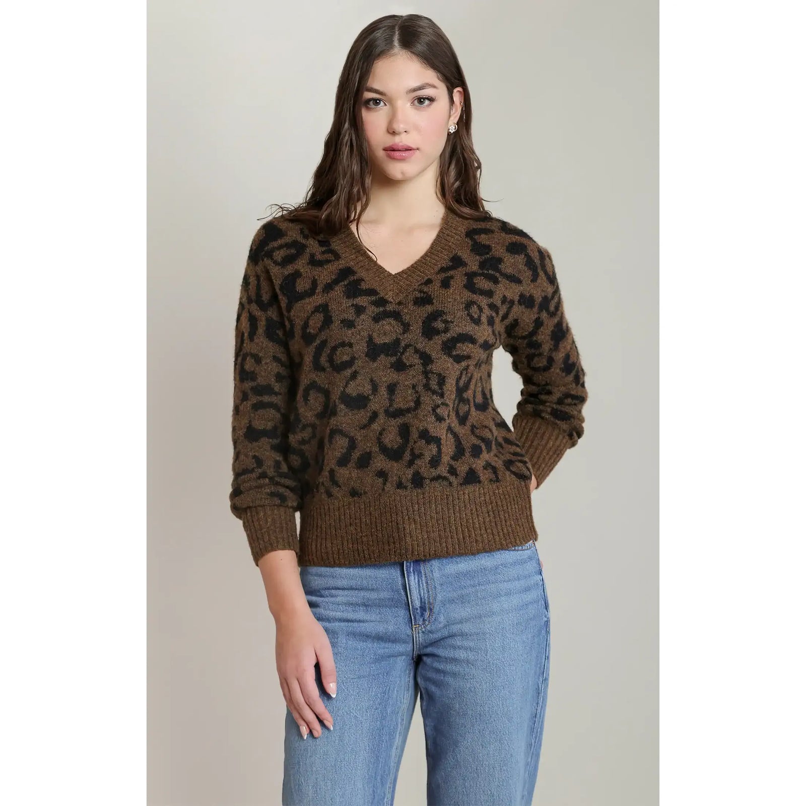 Brown and black leopard print V-neck sweater with long sleeves and ribbed cuffs paired with blue jeans.