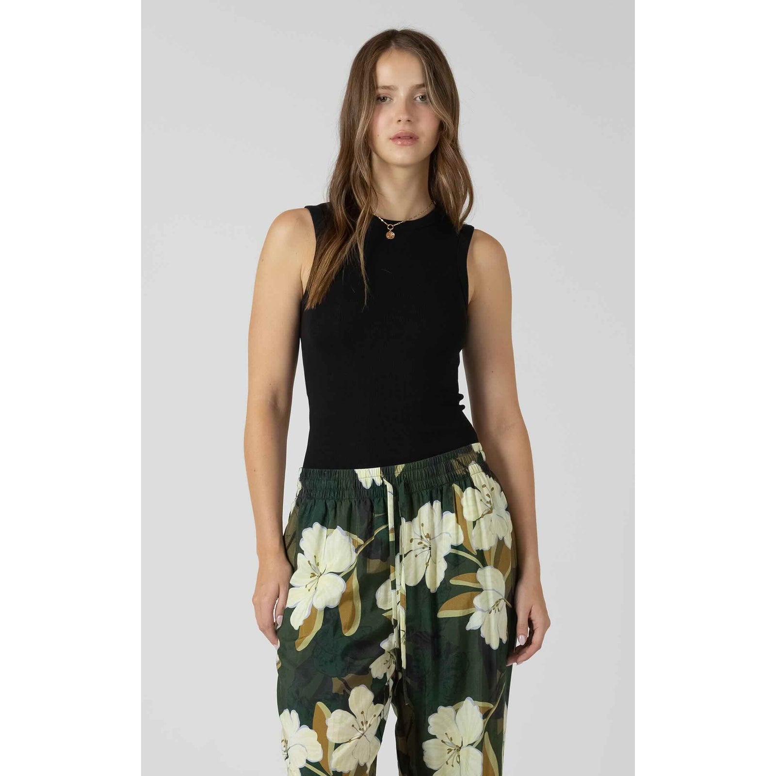 Dex Ribbed Tank black ribbed sleeveless top worn by a model with green floral pants.
