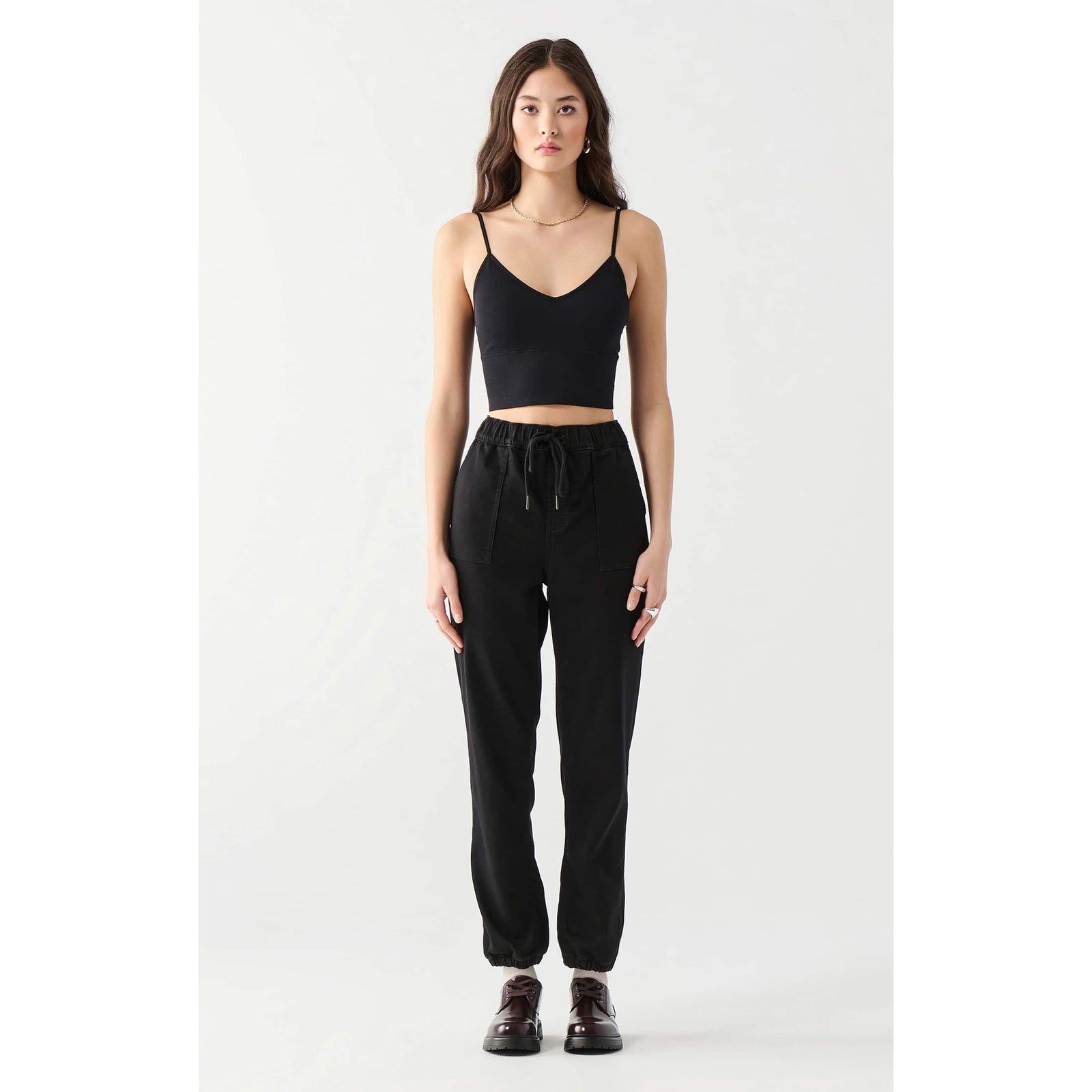 Model wearing Dex Seamless Bra Top, black cotton-spandex cropped top with thin straps.