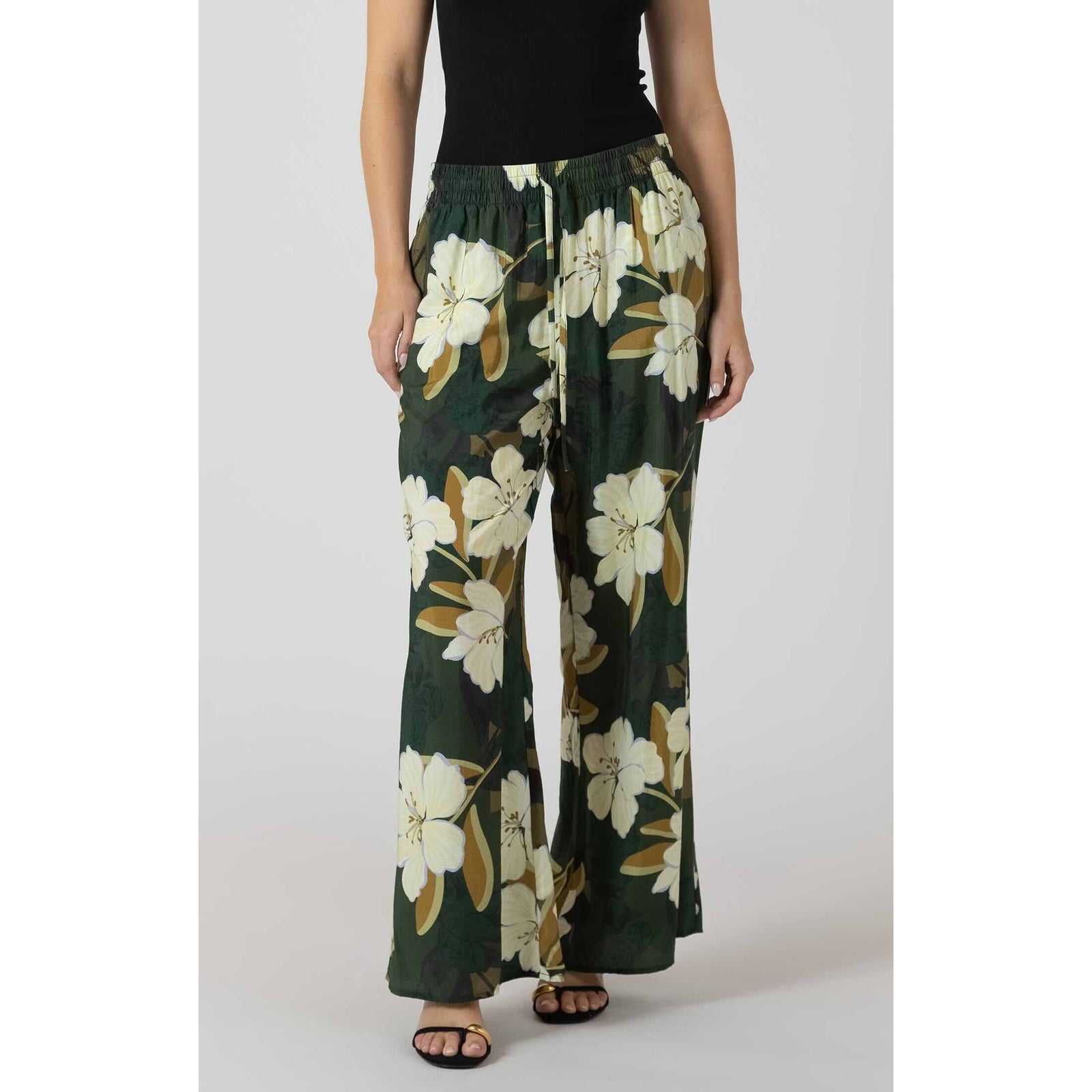 Dex Wide Leg Flowy Pants with large white florals on dark green, elastic waistband, worn with a black top.