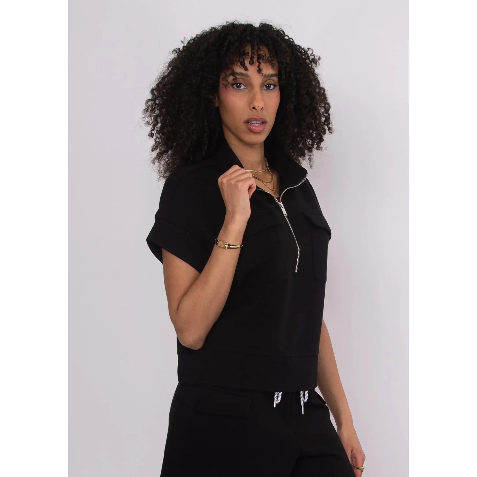 Model wearing Dua Soft Knit 1/2 Zip Top in black with short cuffed sleeves and a breezy, relaxed fit.