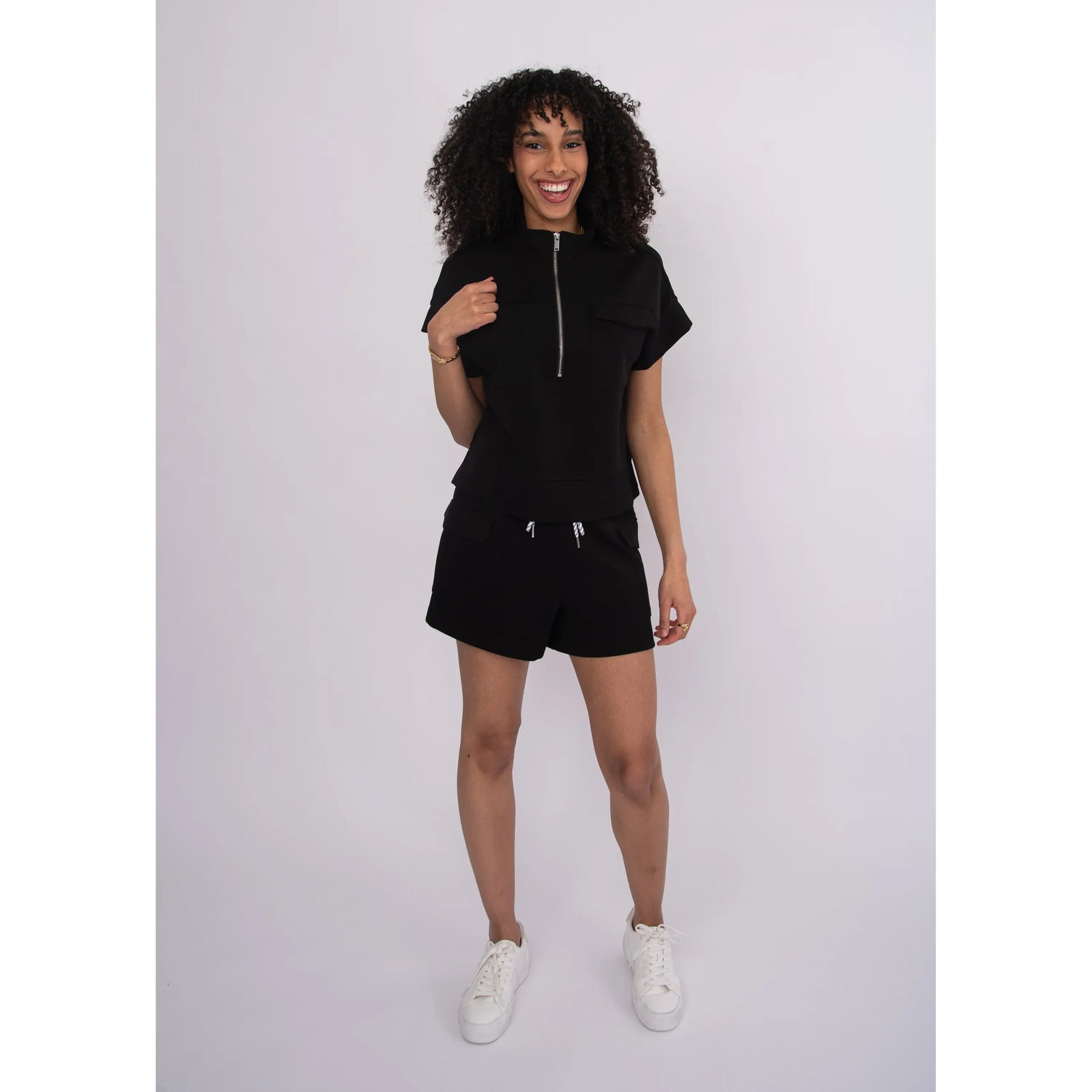 Model wearing Dua Soft Knit 1/2 Zip Top in black with short sleeves and zip front.