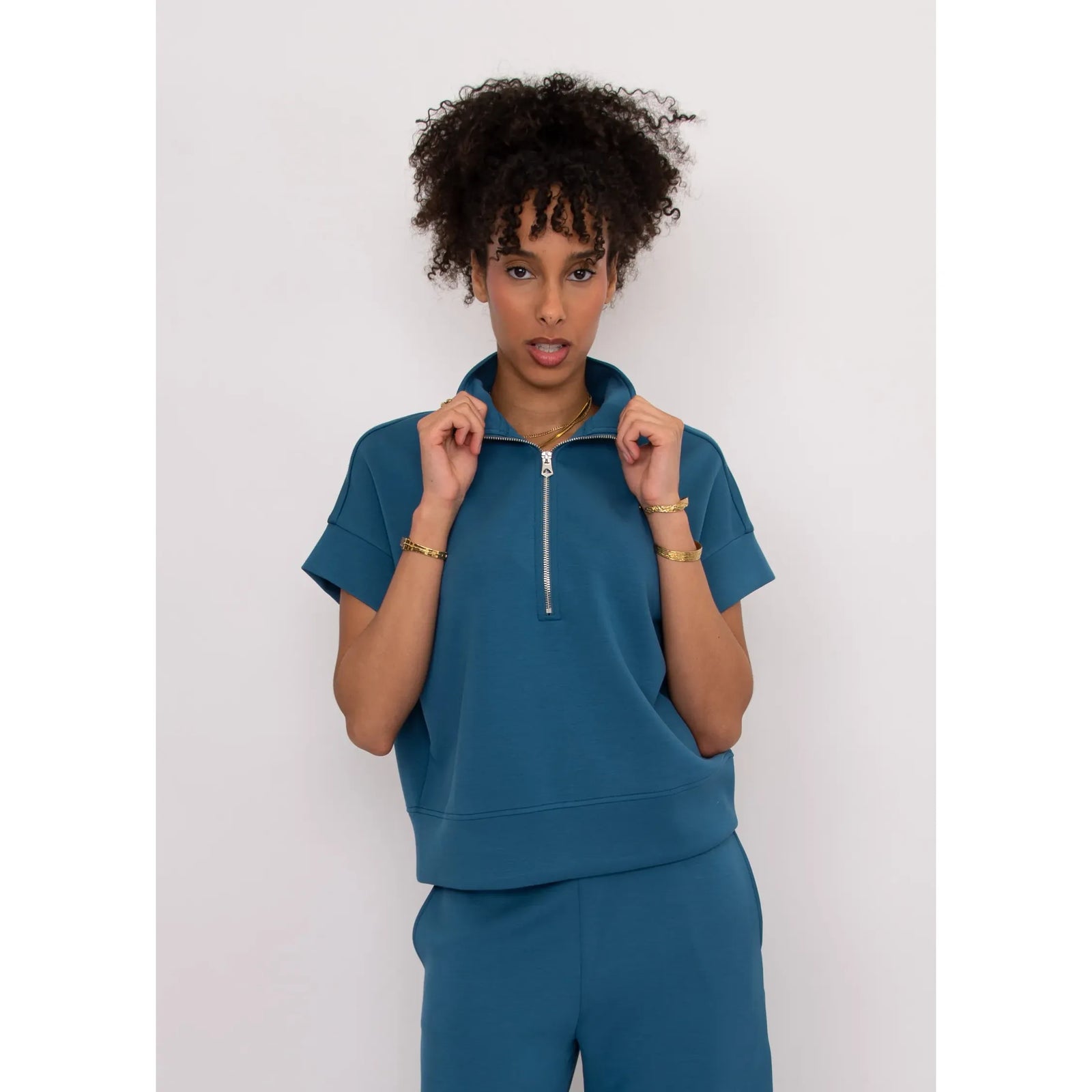 Dua Soft Knit 1/2 Zip Top in teal with short sleeves and relaxed fit on model.