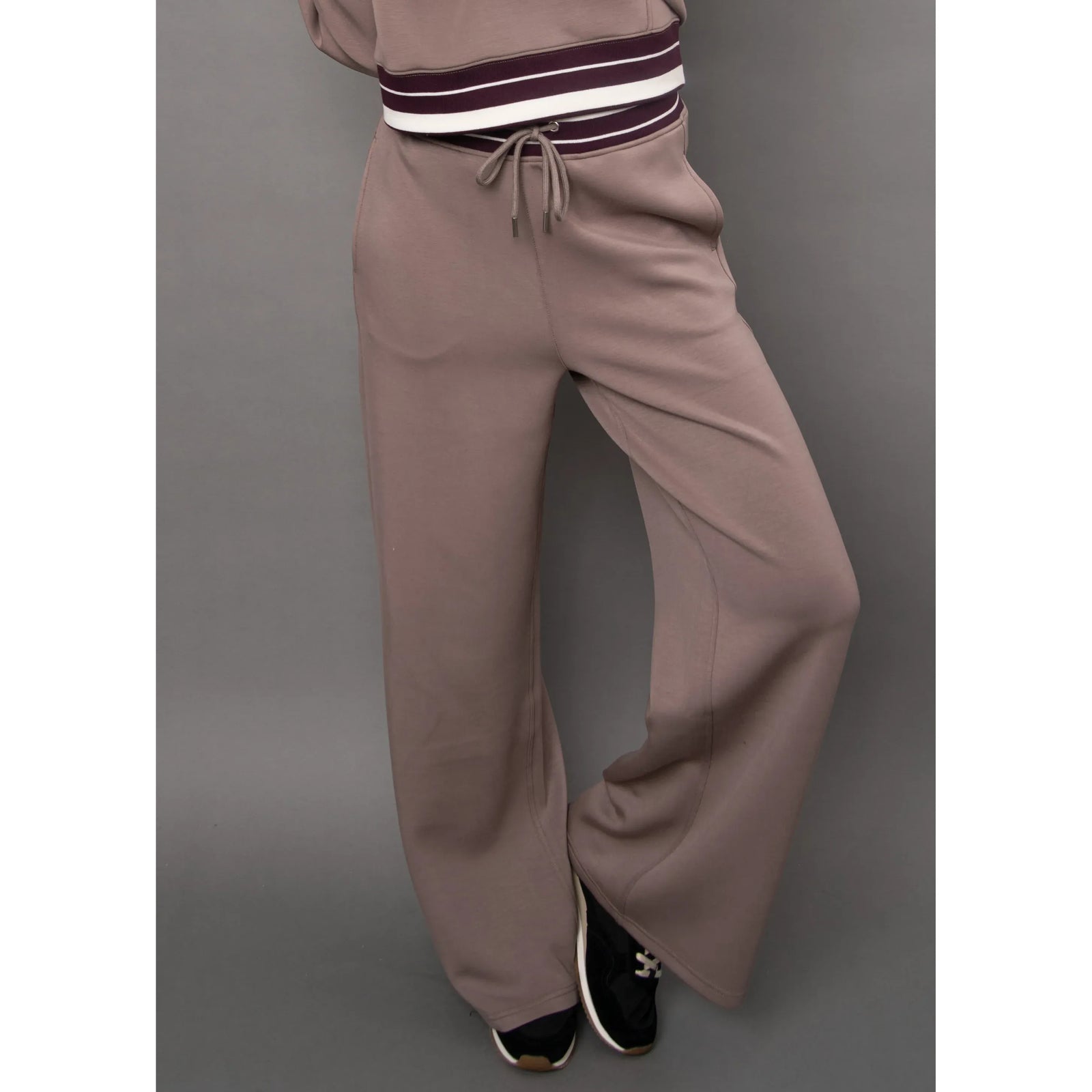 Taupe high-waisted athletic trousers with a self-tie drawstring waist and relaxed, wide-leg drape for a modern silhouette.