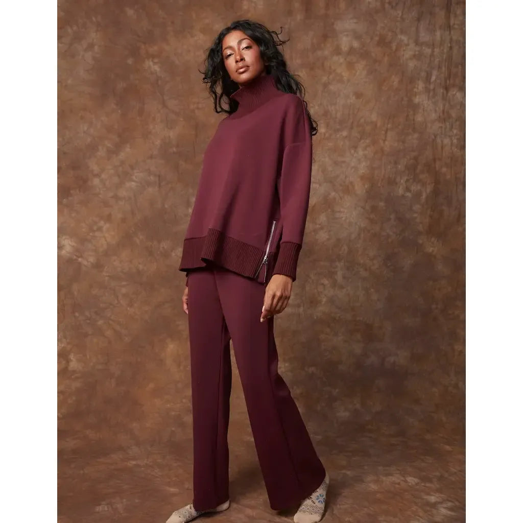 Model wearing prune Florine soft-knit pull-on flare pants with a matching oversized turtleneck sweater.