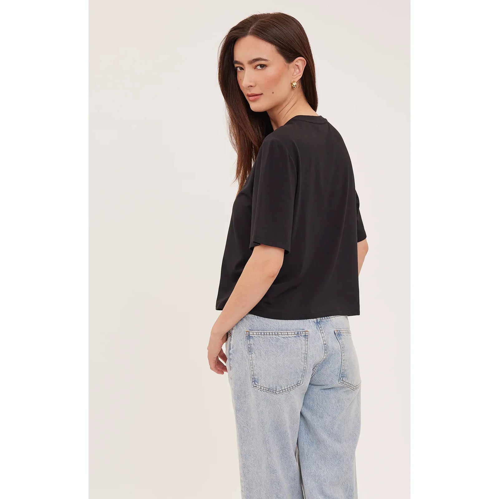 Back view of a model wearing a black relaxed fit Codie T-shirt with short sleeves and light blue jeans.