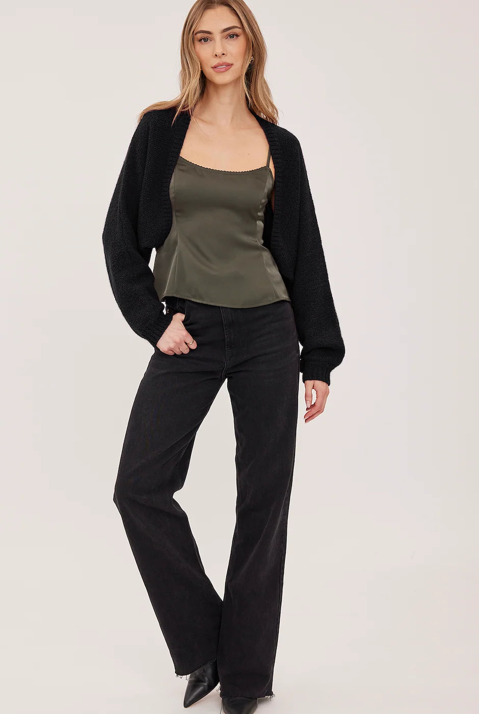 Black cropped open-front cardigan in soft bouclé with voluminous sleeves and fitted rib cuffs, styled over a green satin camisole.