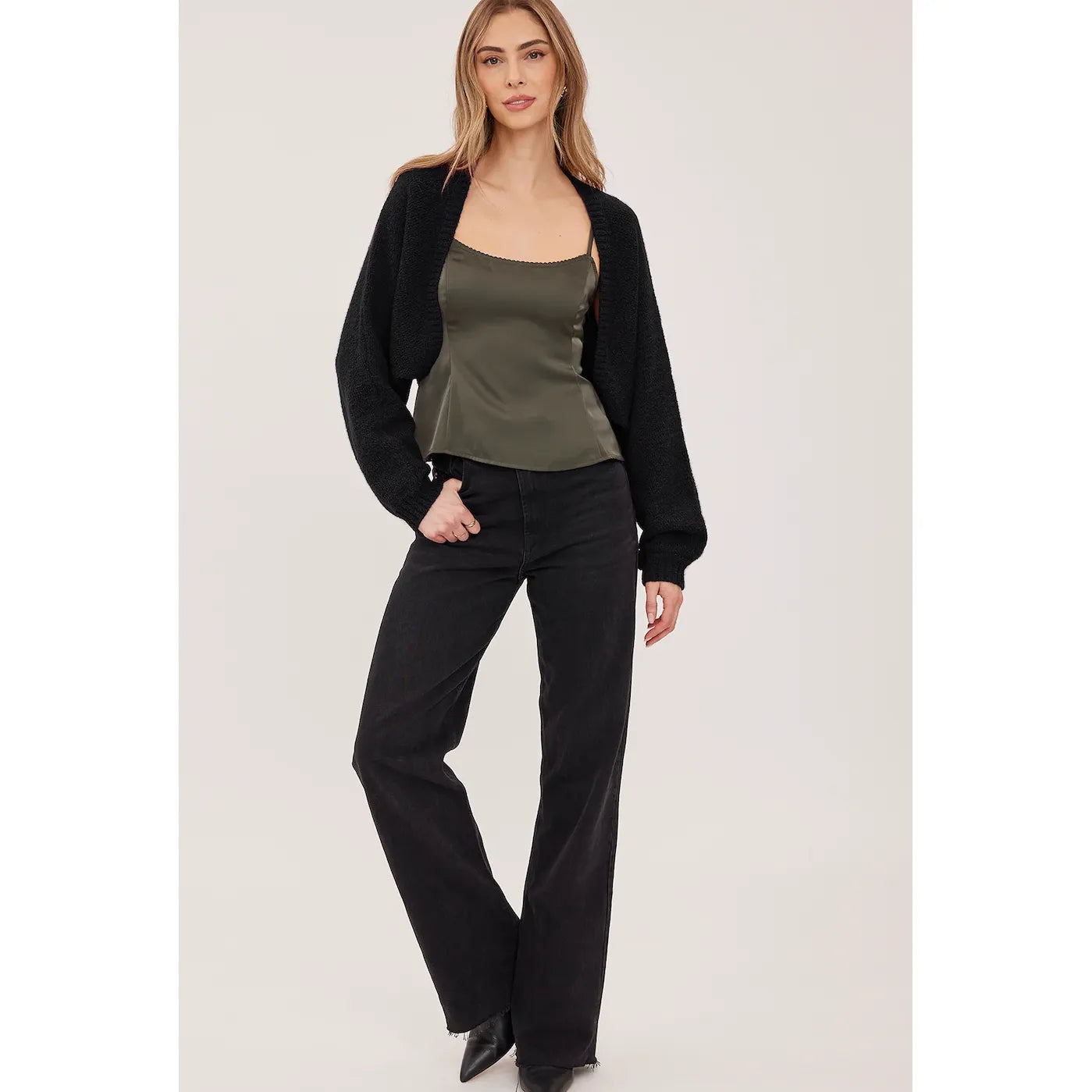 Black cropped open-front cardigan in soft bouclé with voluminous sleeves and fitted rib cuffs, styled over a green satin camisole.