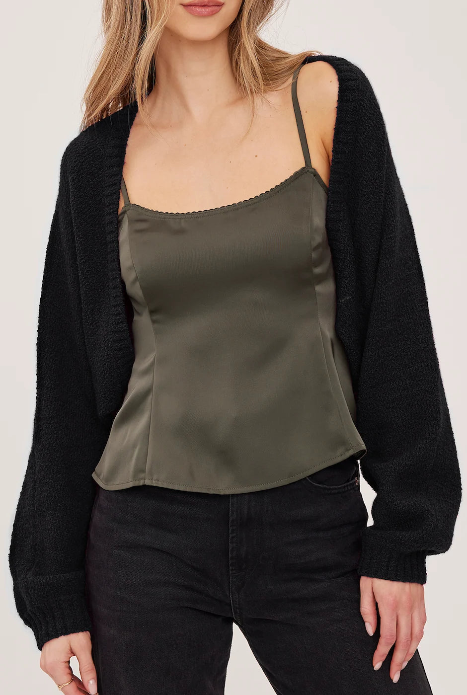 Black cropped bouclé cardigan with voluminous sleeves and fitted rib cuffs, worn open over a green camisole.