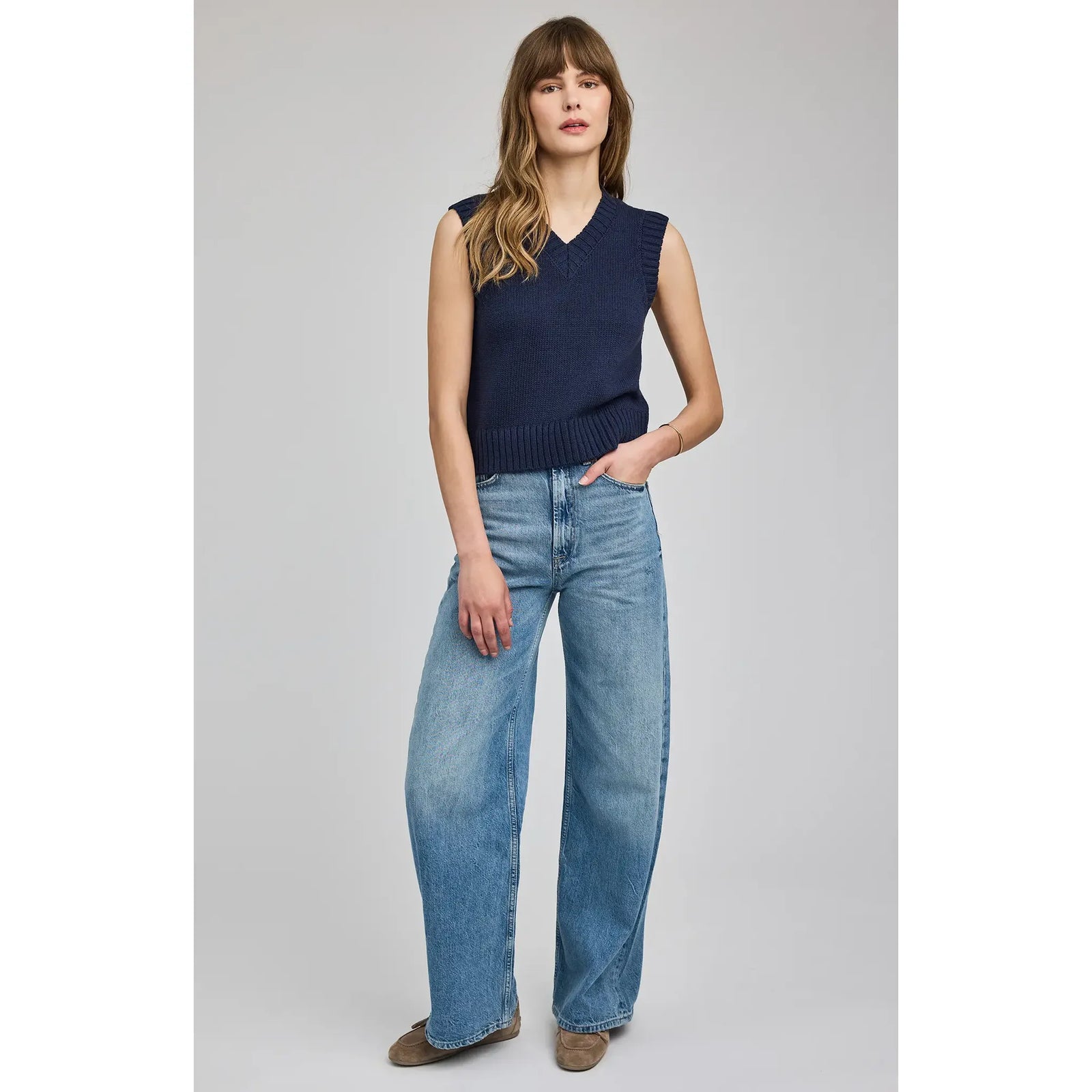Model wearing Gentle Fawn Pippa V-Neck Tank: navy sleeveless knit with V-neck and ribbed hem, wide-leg jeans.