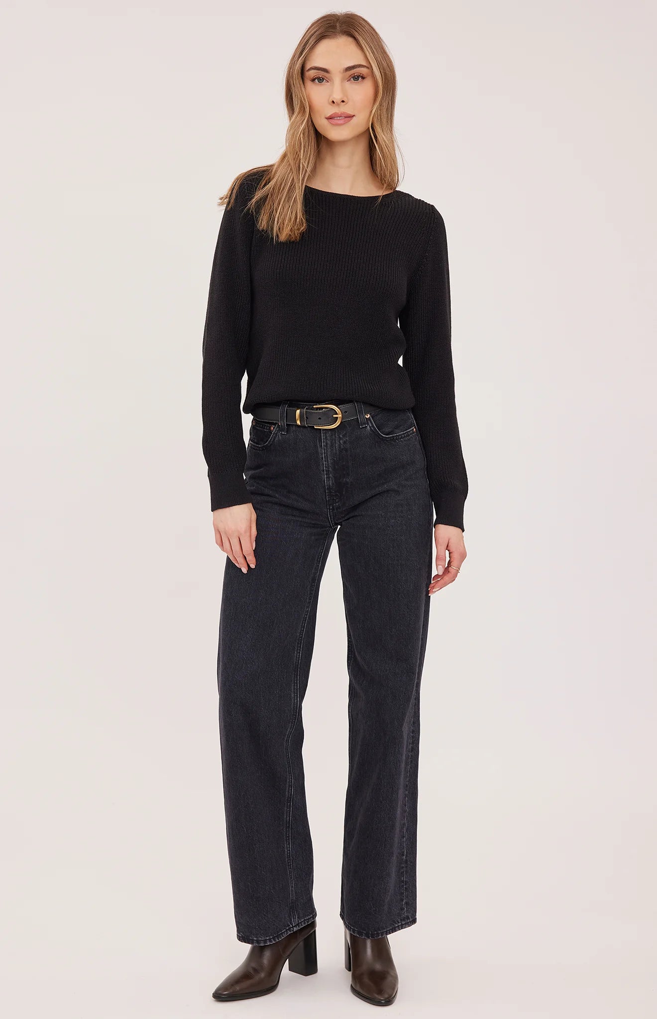 Black slim-fit Ramona sweater with boat neckline and half-cardigan knit, paired with dark jeans and brown boots.