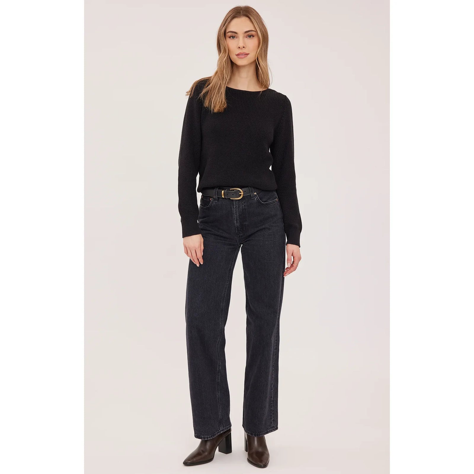 Black slim-fit Ramona sweater with boat neckline and half-cardigan knit, paired with dark jeans and brown boots.