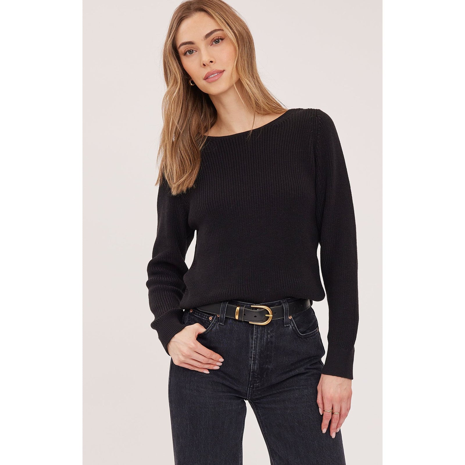 Black slim-fit Ramona sweater with wide boat neckline and half-cardigan-stitch knit, paired with dark jeans and gold belt.