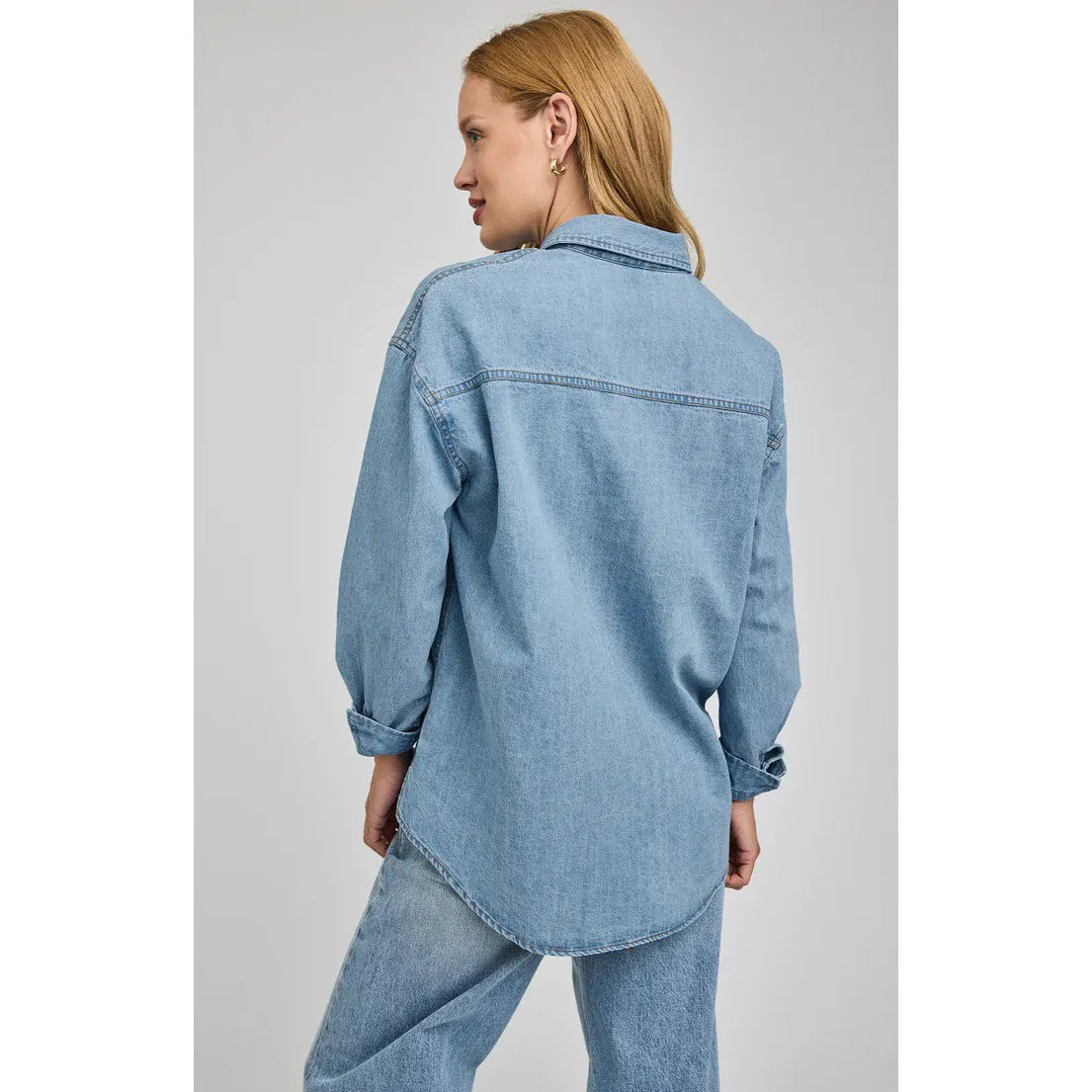 Gentle Fawn Whitney light-wash denim shirt shown on a model, back view with curved hem and rolled sleeves.