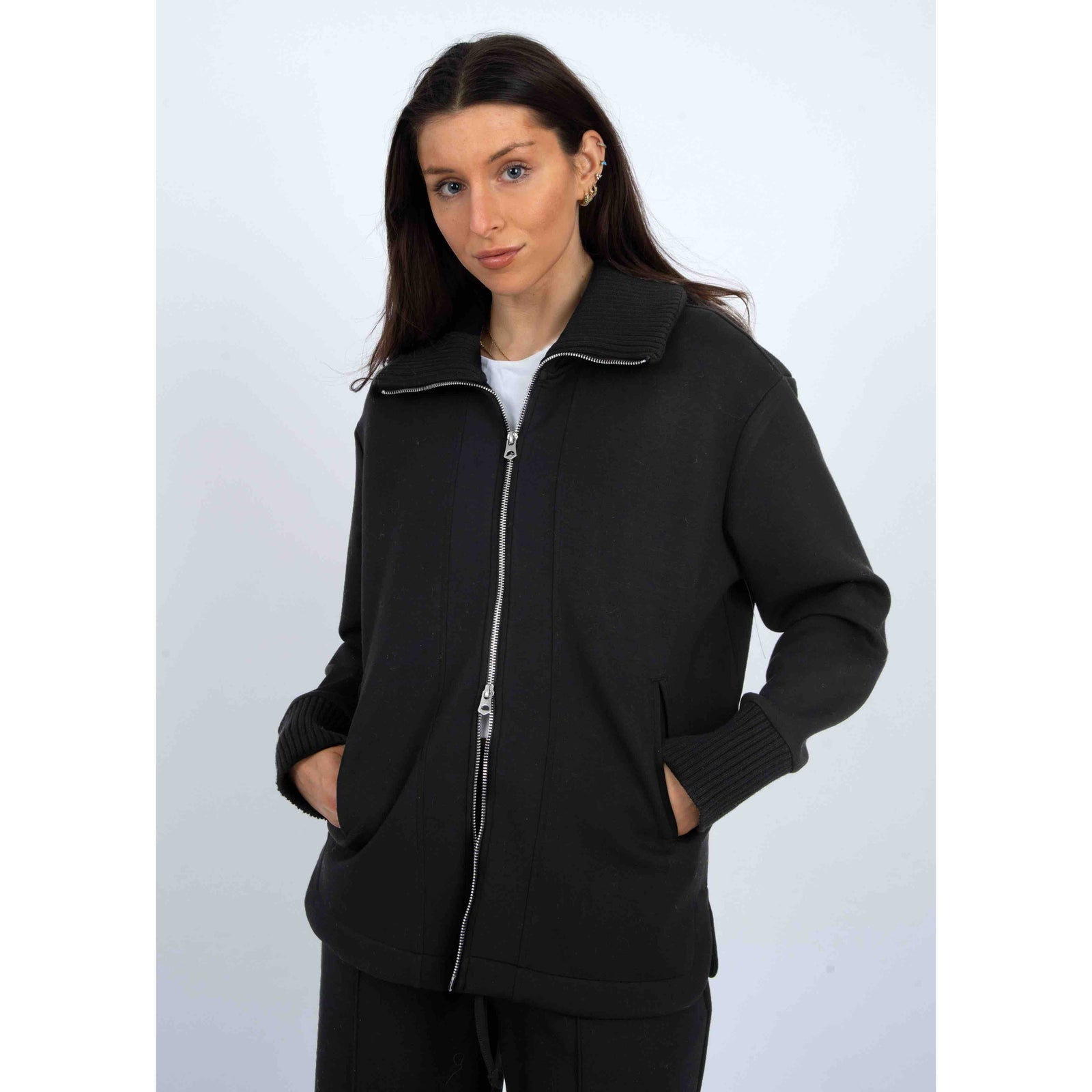 Black Judia Soft Knit Zip Sweater with two-way zipper, oversized silhouette, ribbed collar and cuffs, model in pockets.