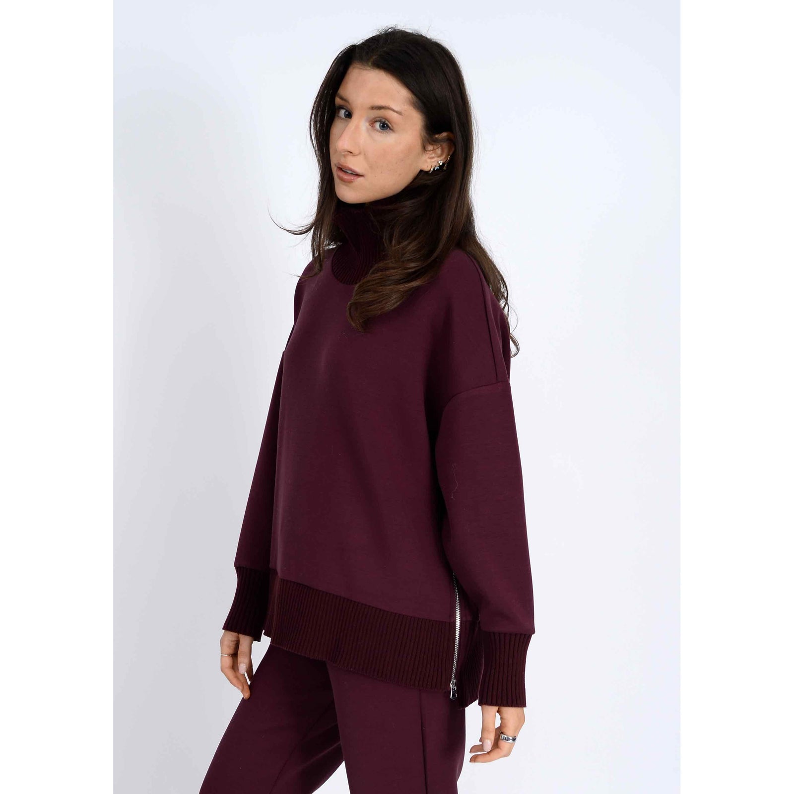 Model in Katelyn Soft Knit Sweater in burgundy, oversized modal knit with ribbed cowl neck, ribbed hem, side zipper.