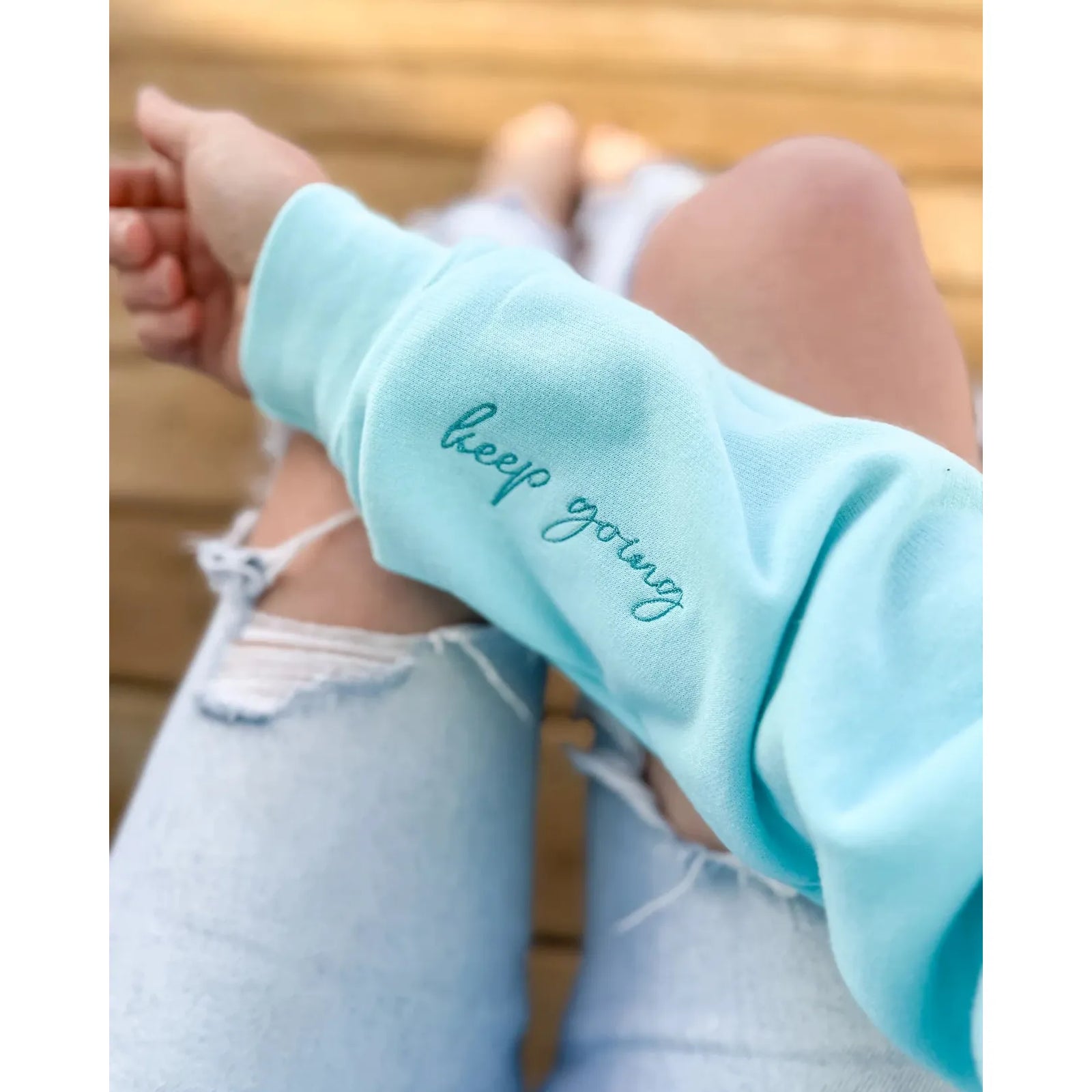 Stay motivated in the Keep Going Embroidered Crew, showcasing a heart and inspiring script on a mint background.