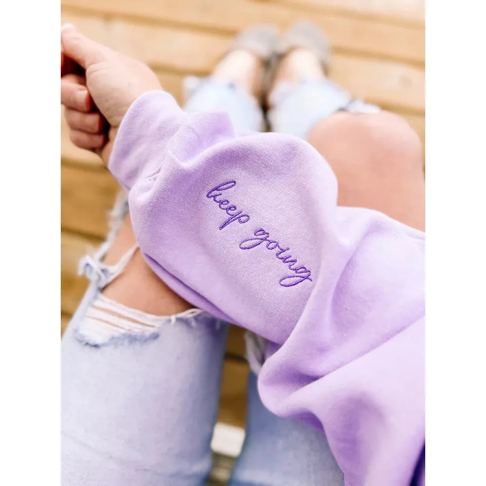 Stylish Keep Going Embroidered Hoodie in lavender, featuring inspiring script on the sleeve for motivation.