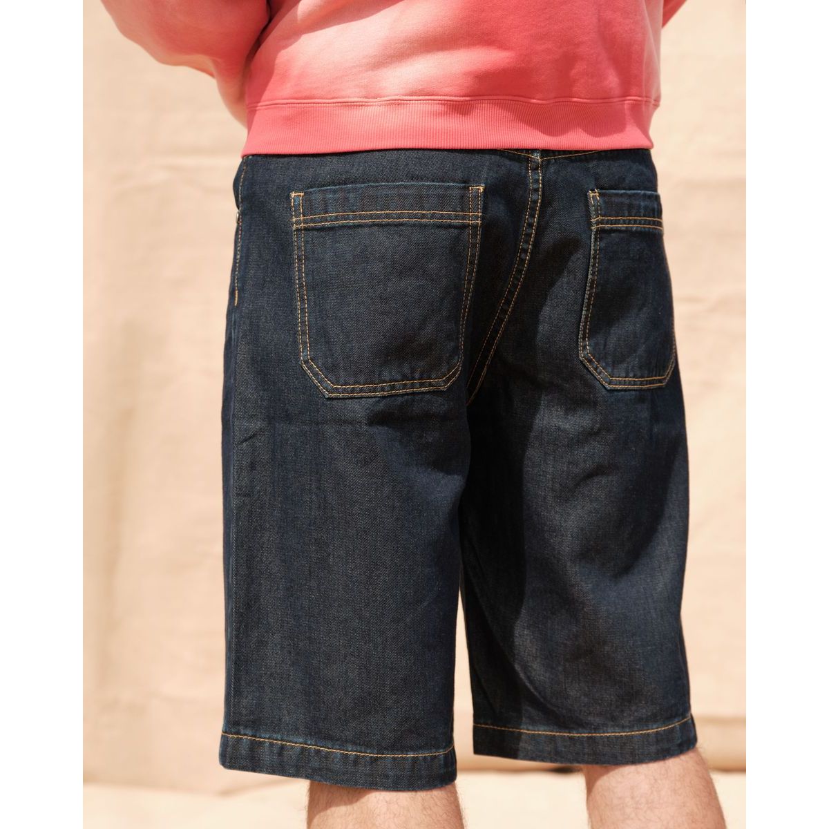 Back view of Kuwalla Bermuda Denim Shorts in dark denim with yellow stitching, relaxed fit, back pockets