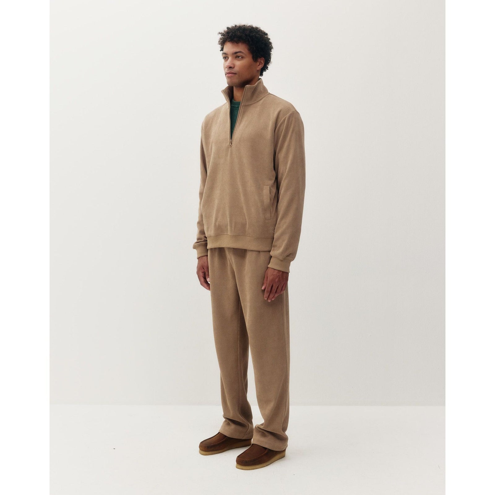 Man wearing a tan chenille 1/4 zip sweatshirt and matching pants. Cozy textured quarter-zip pullover with clean, modern casual style.