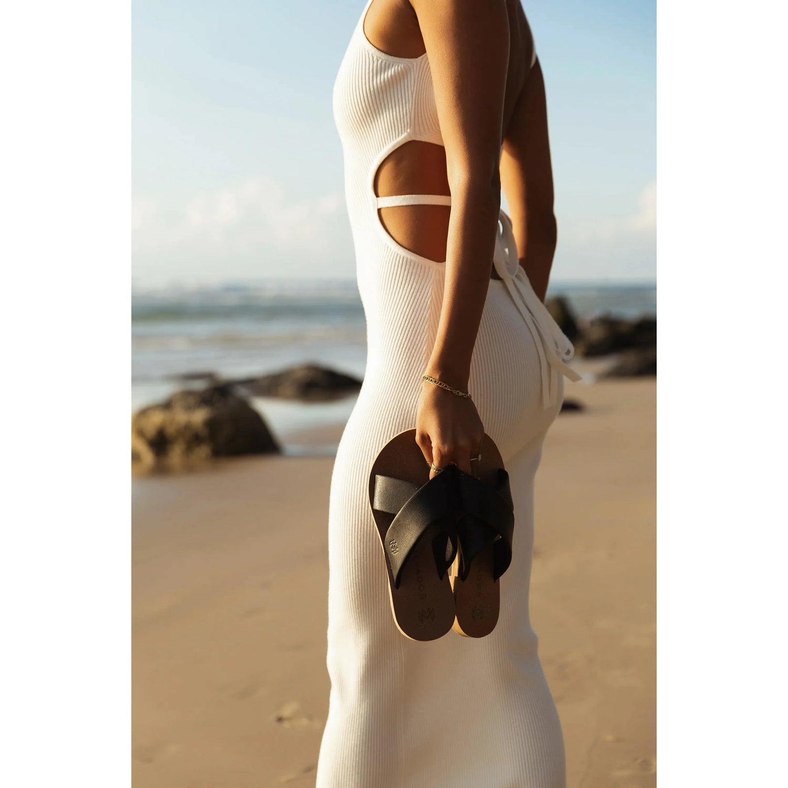 Stylish Malvados Ellie Cross sandals held by a model on the beach, showcasing comfort and chic design.