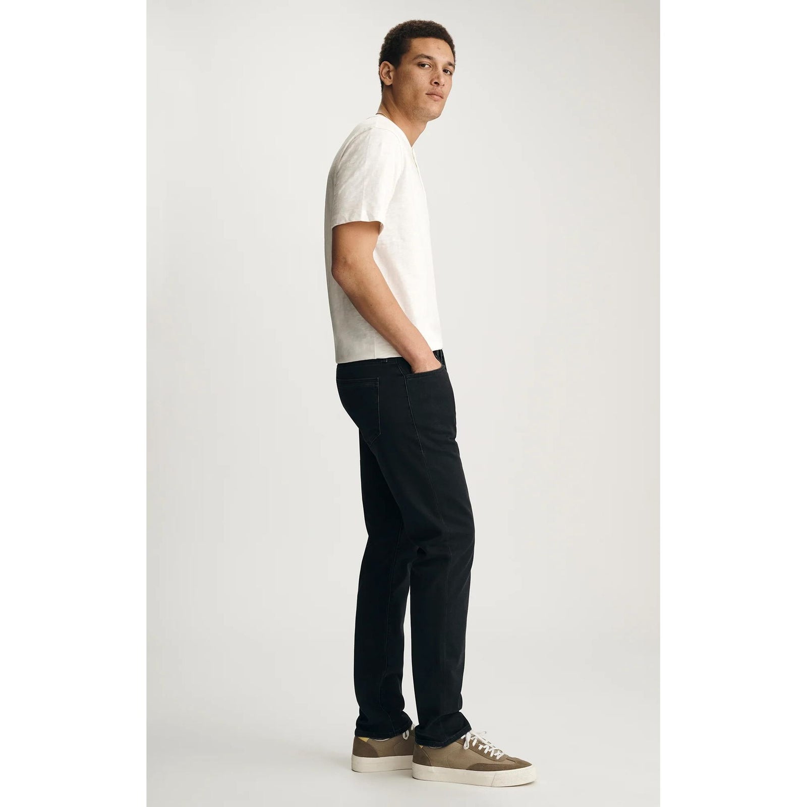Male model in white tee wears Mavi Jake Smoke Explorer Denim in washed-out black, slim through hip and leg.