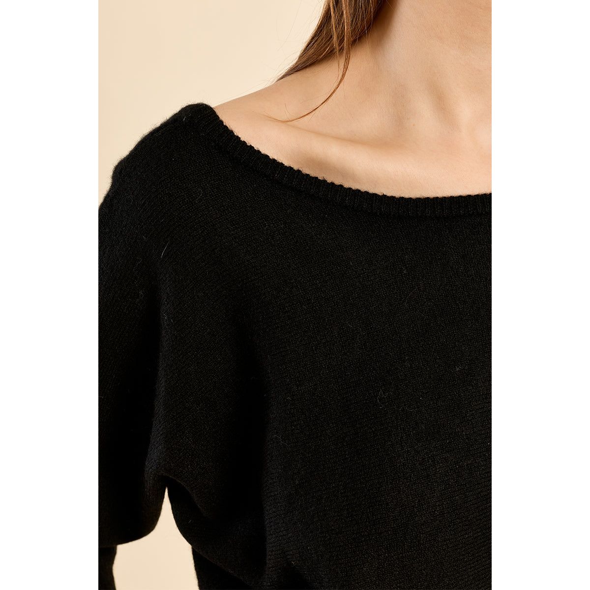 Black open-back 3/4 sleeve sweater with boat neckline and ribbed cuffs. Relaxed-fit knit blending cozy comfort and chic style.