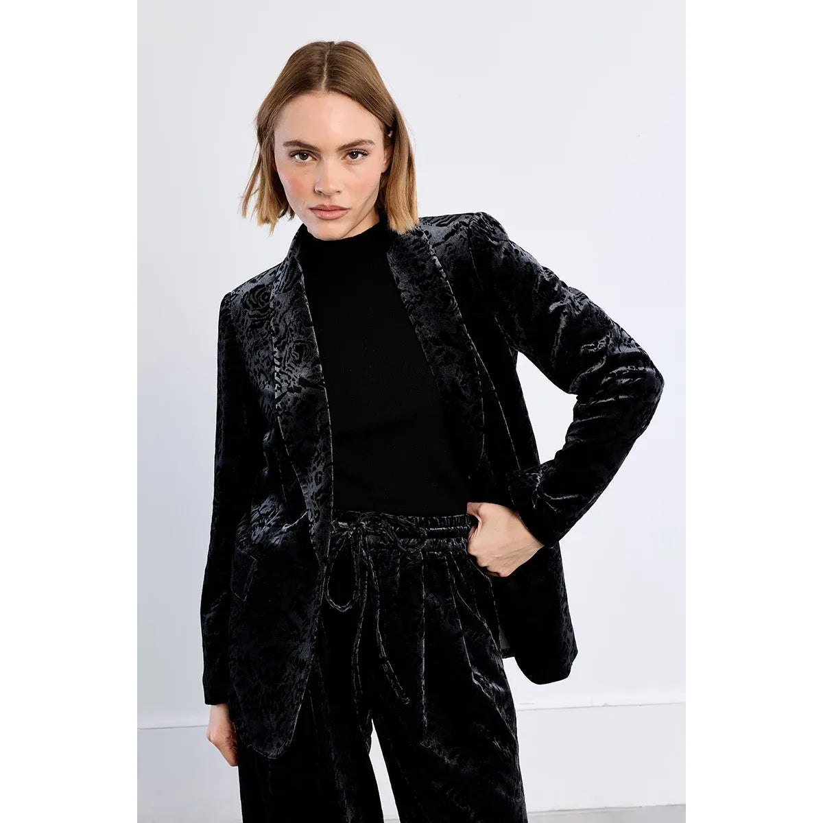 Black floral velvet blazer with V-neck and front button closure, styled over a black turtleneck top.