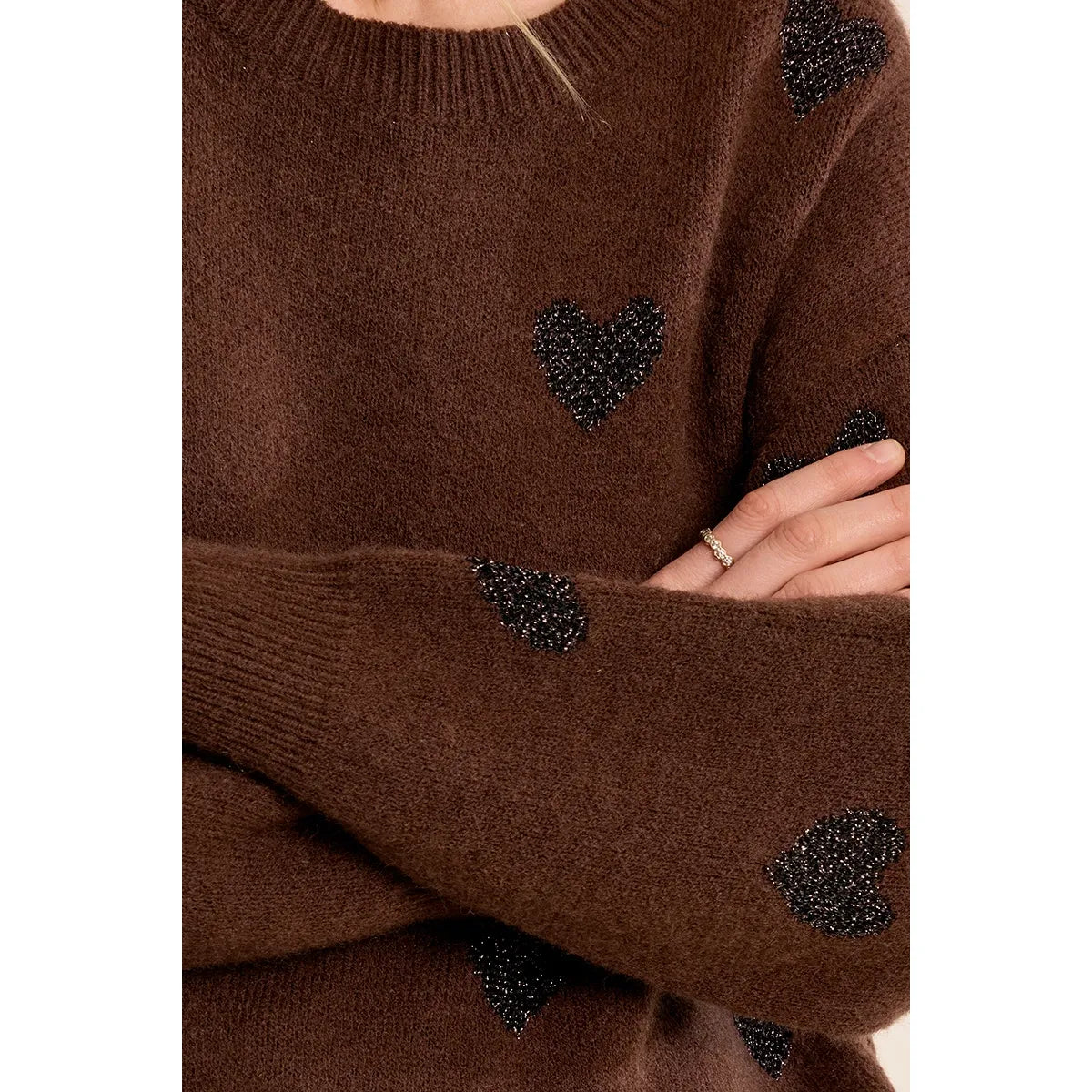 Brown knit sweater with black glittery heart pattern, round neckline, and straight sleeves for a cozy sparkle.