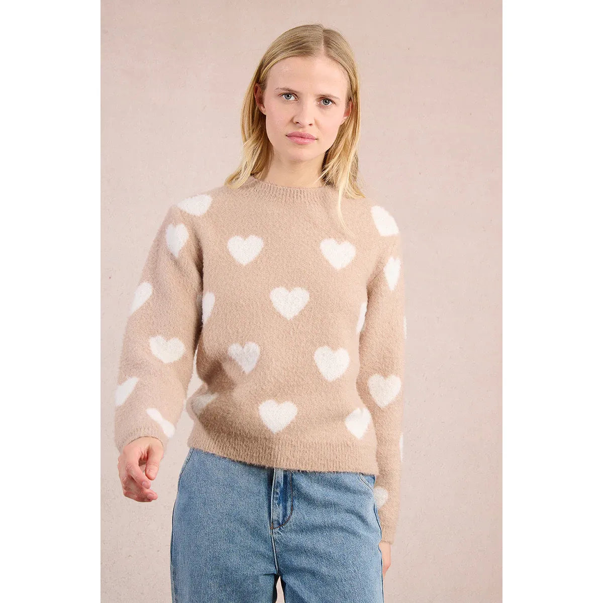 Molly Bracken Heart Sweater: beige fuzzy knit with white hearts, round neckline, worn with blue jeans.