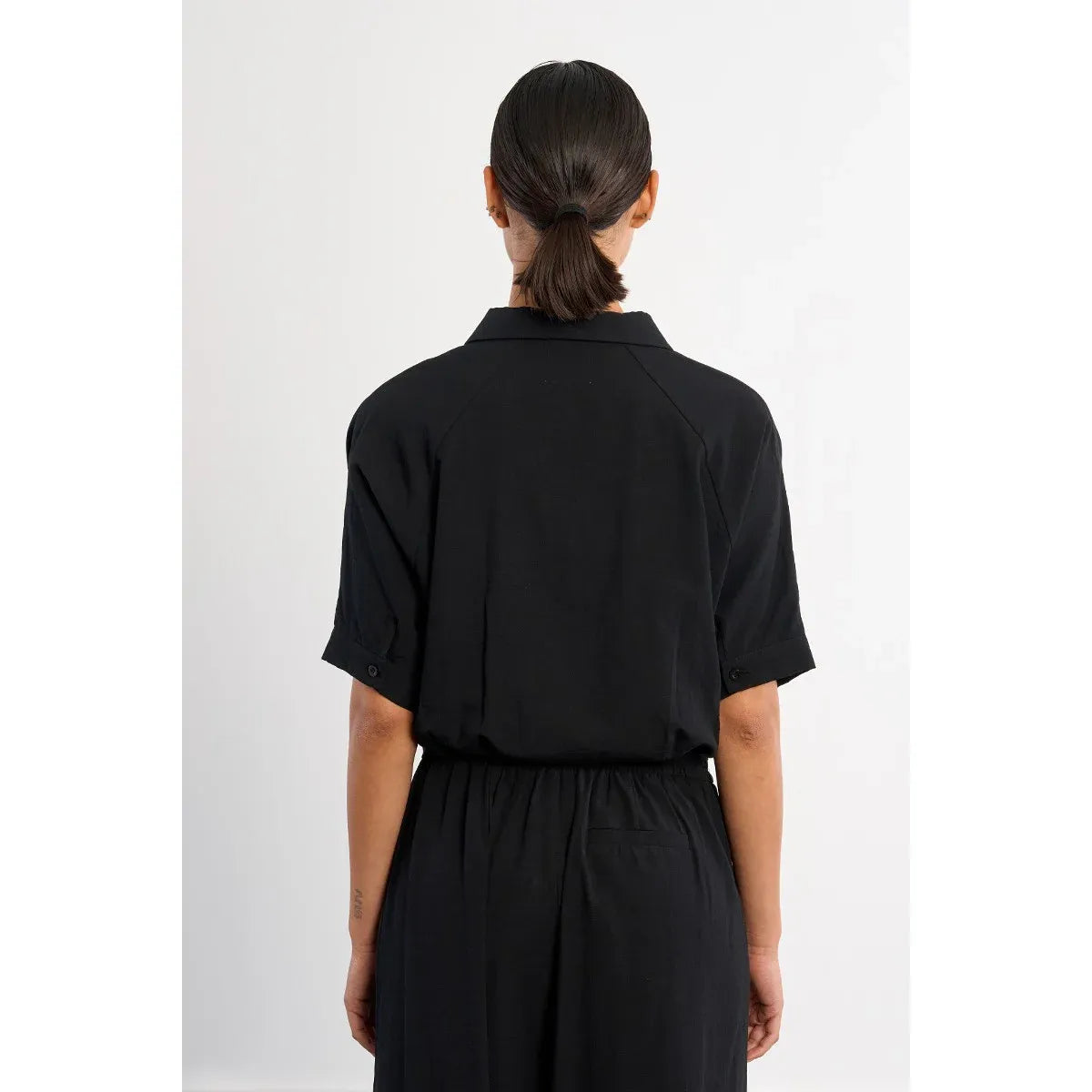 Back view of a black Molly Bracken knotted blouse with short rolled sleeves and an elastic waist.