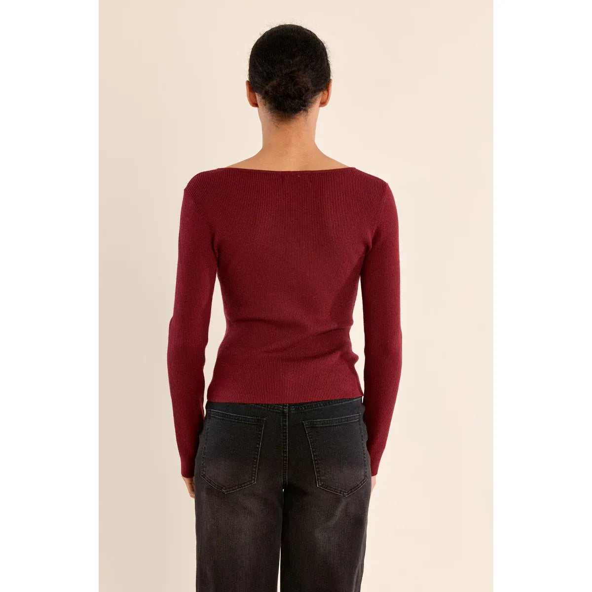 Back view of a maroon fine ribbed sweater with a boat neck, tucked into dark denim jeans.