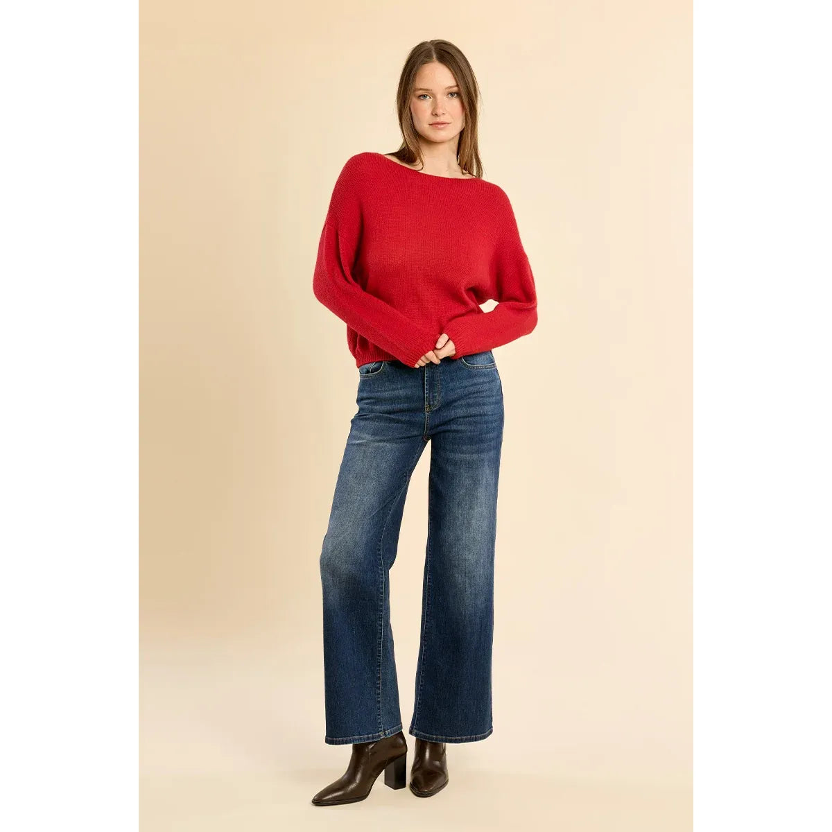 Red round neck knit sweater with low armholes and ribbed trim, styled with blue wide-leg jeans and brown boots.