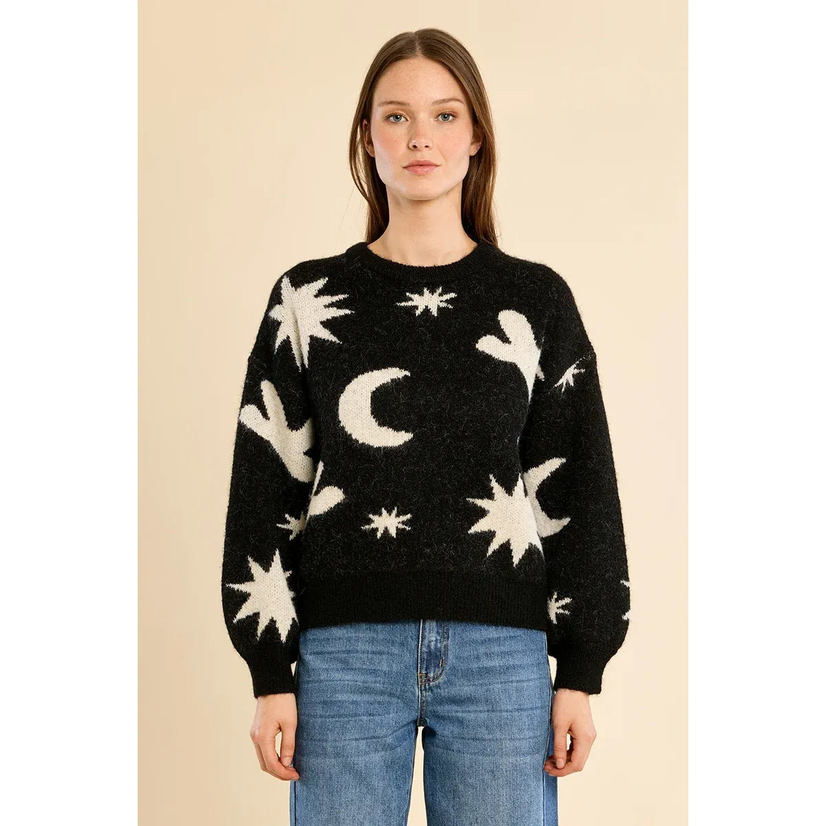 Black knit sweater with white star and moon pattern, balloon sleeves, and ribbed trim paired with blue jeans.