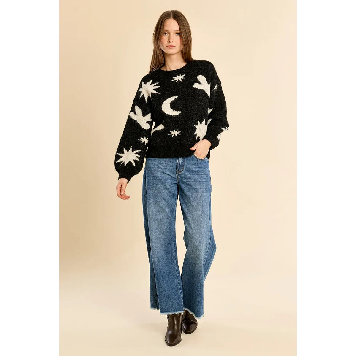 Black knit sweater with white star, moon, and dove patterns, balloon sleeves, paired with wide-leg jeans and boots for a fall look.