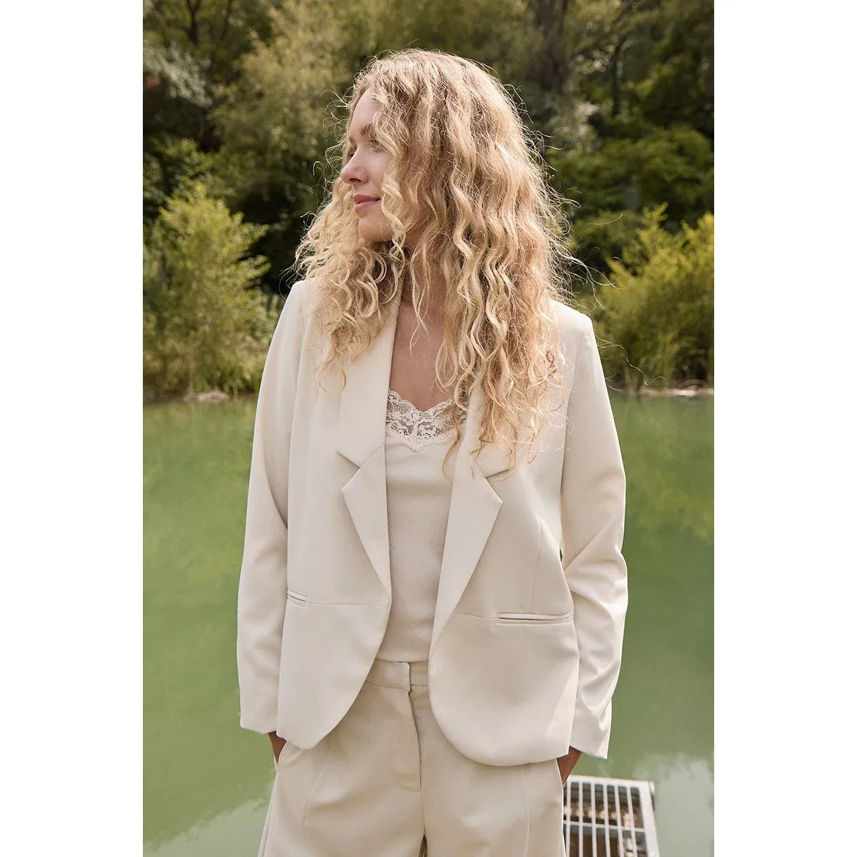 Cream Molly Bracken straight blazer with matching pants, worn by a woman outdoors by a lake.