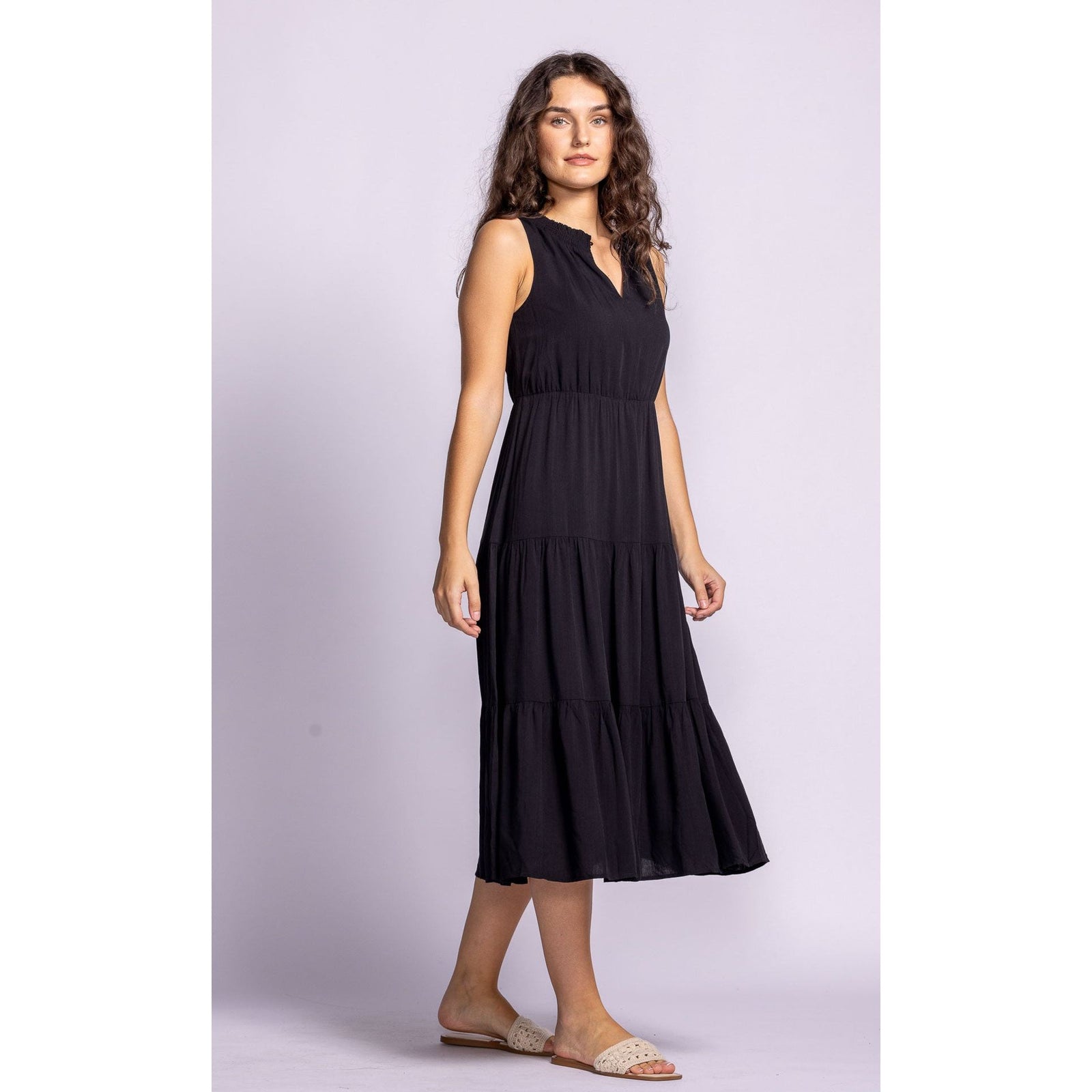 Stylish model showcasing the Pink Martini Jennifer Dress, a chic tiered black midi made from lightweight rayon.