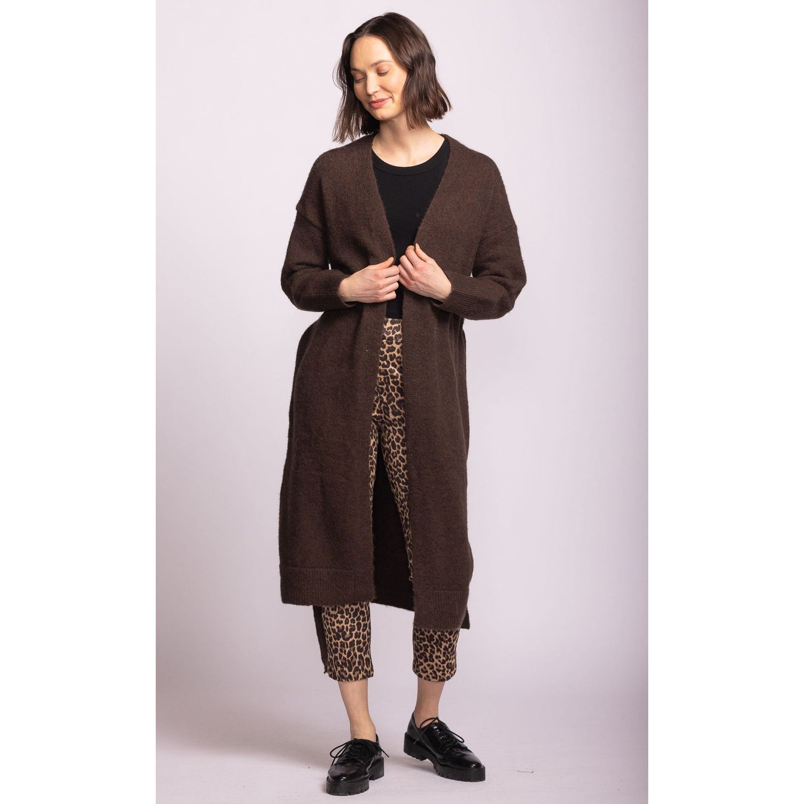 Pink Martini Kiki Sweater in brown, a long belted cardigan worn by a model with leopard-print pants.