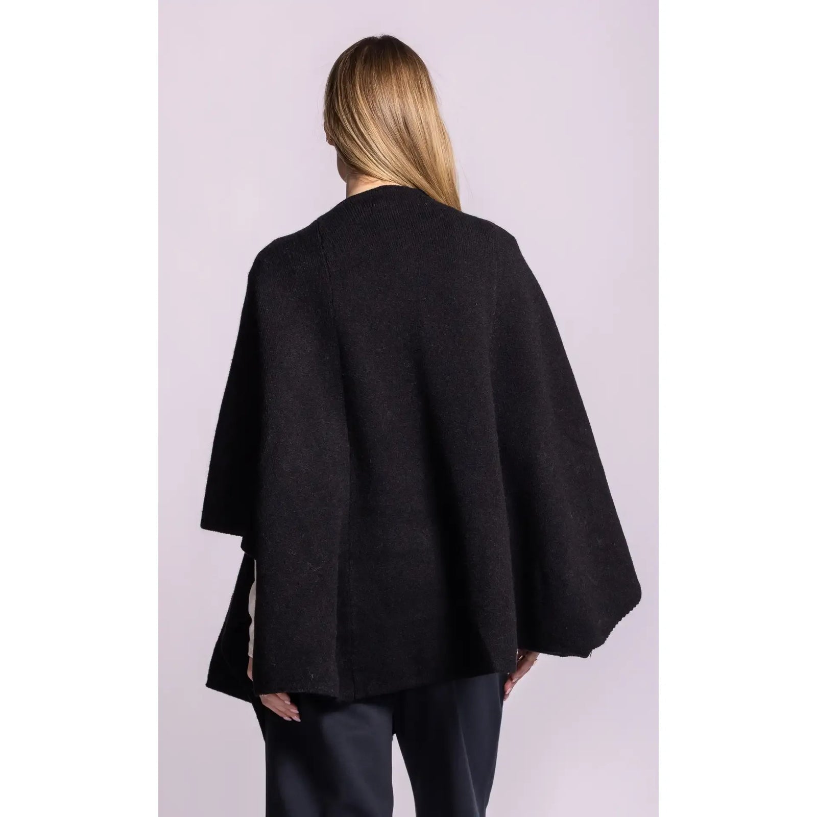 Back view of a black Lennon Wrap Sweater featuring a poncho silhouette, wide open sleeves, and soft knit texture.